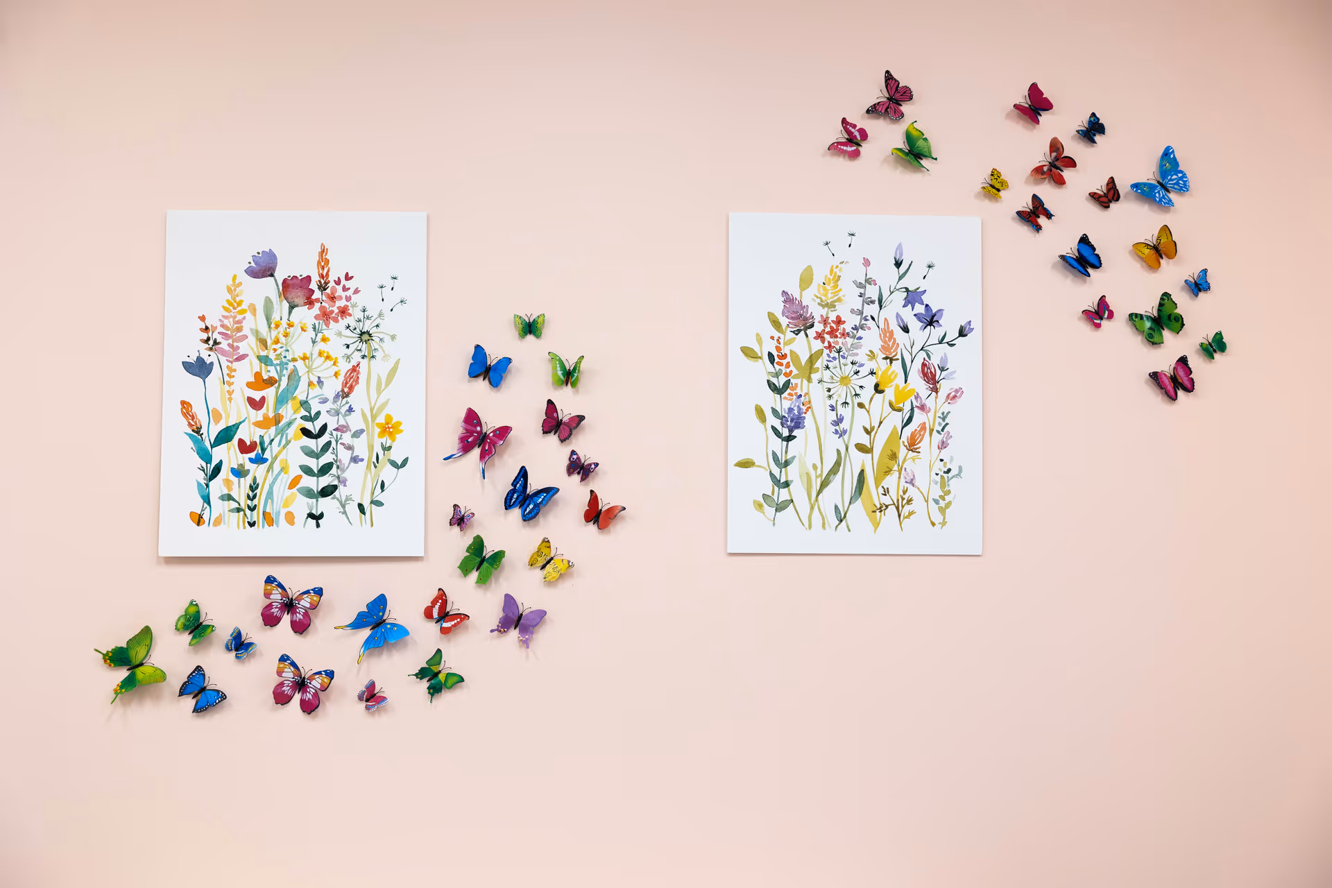 Two framed botanical prints on a peach wall surrounded by colorful butterflies.