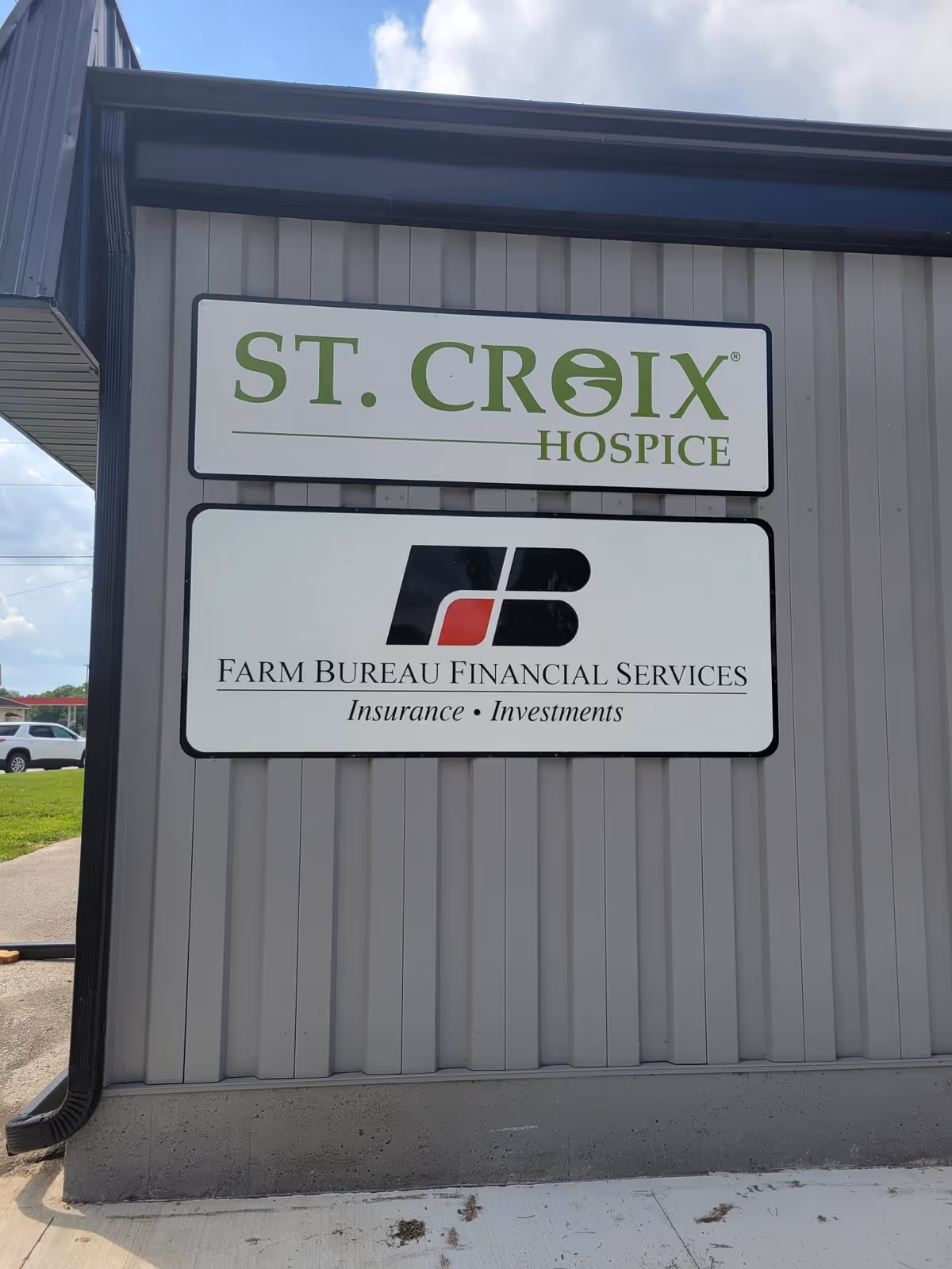 Exterior wall with St. Croix Hospice sign and Farm Bureau Financial Services sign.