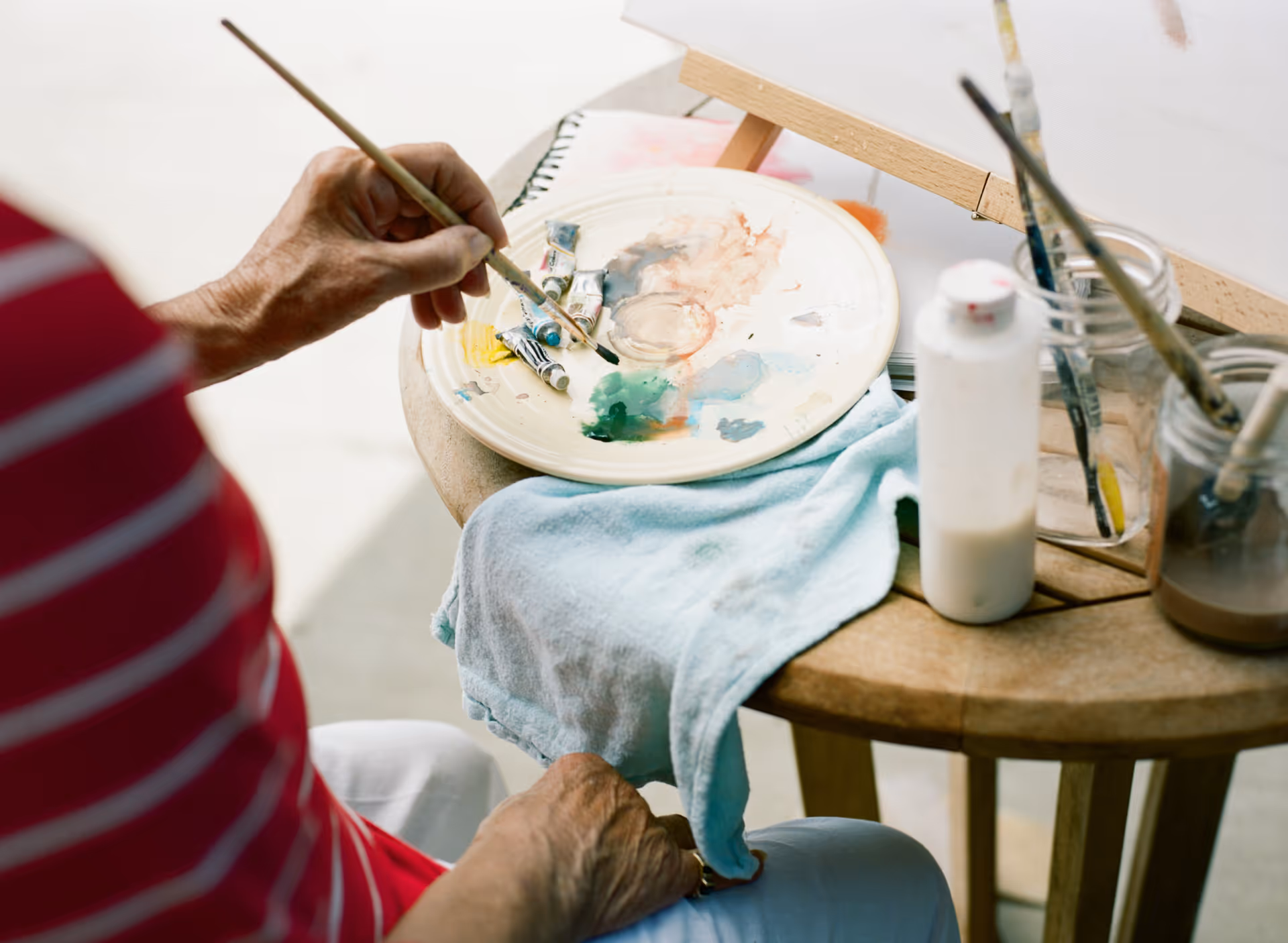 A painter's setup with a palette, brushes, and towels on a wooden table.