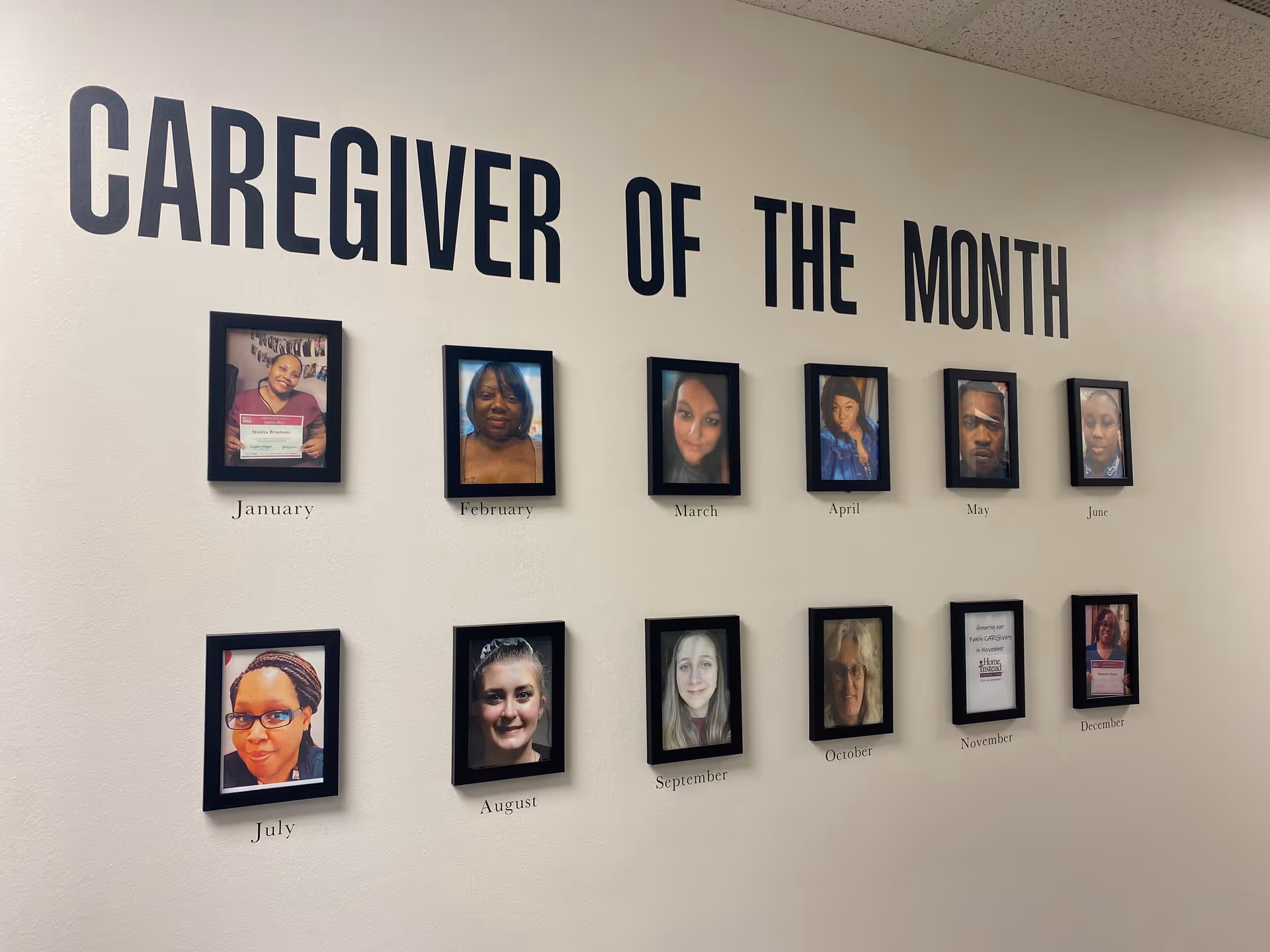 Wall display titled Caregiver of the Month with framed portraits and month captions.
