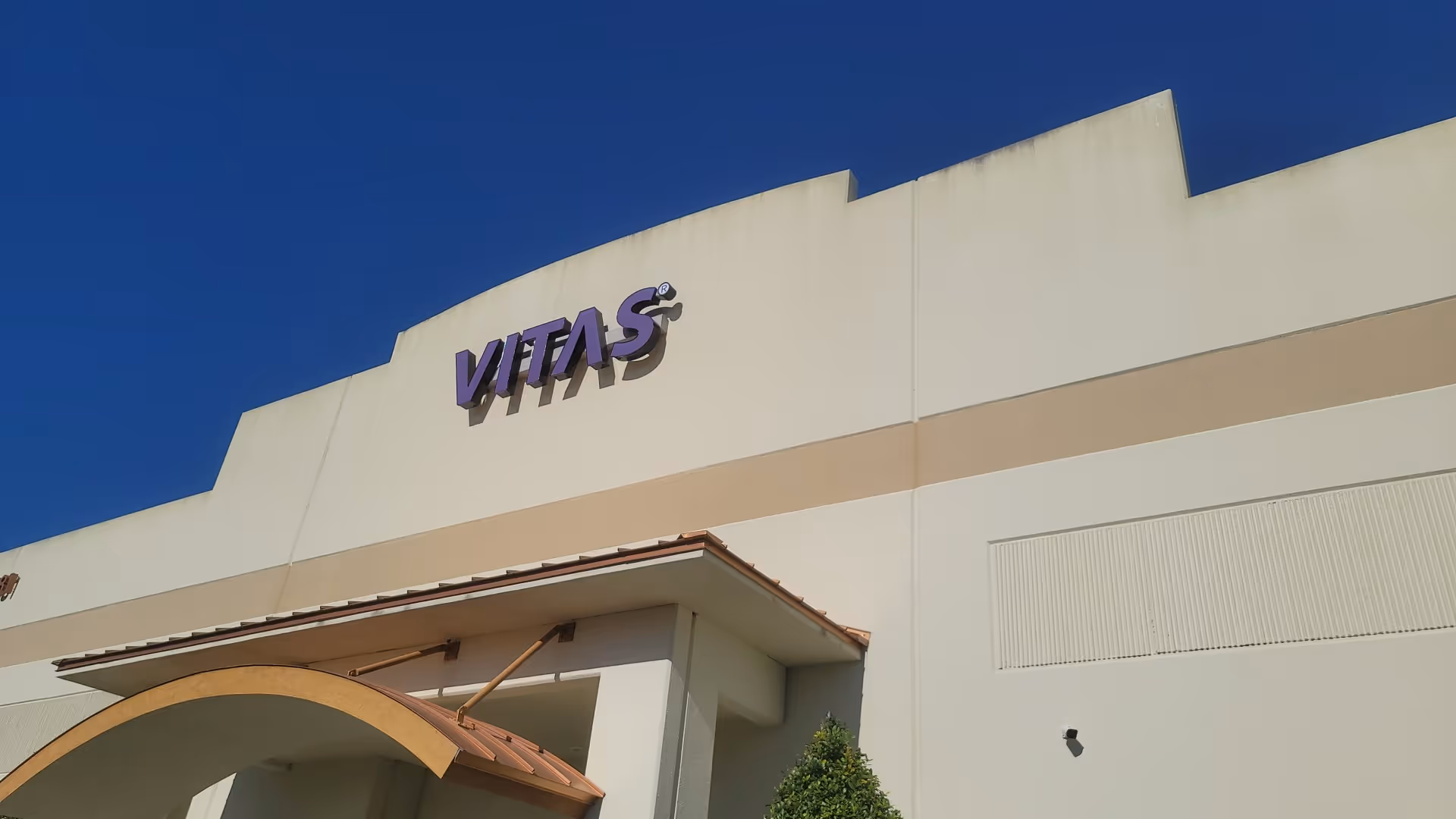 White VITAS Healthcare building exterior under a clear blue sky.