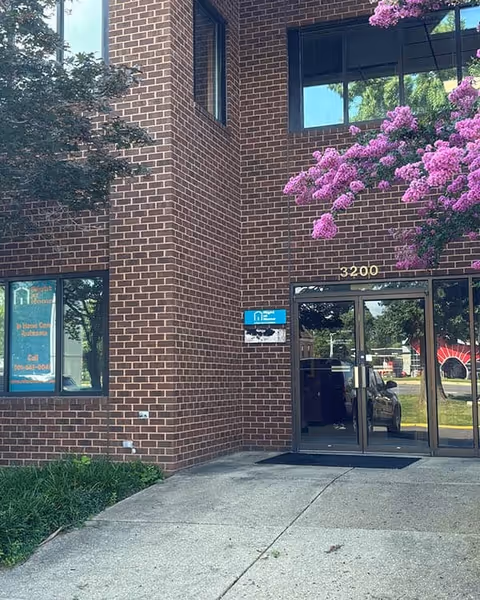 Brick senior living center entrance at 3200 with flowering trees outside.