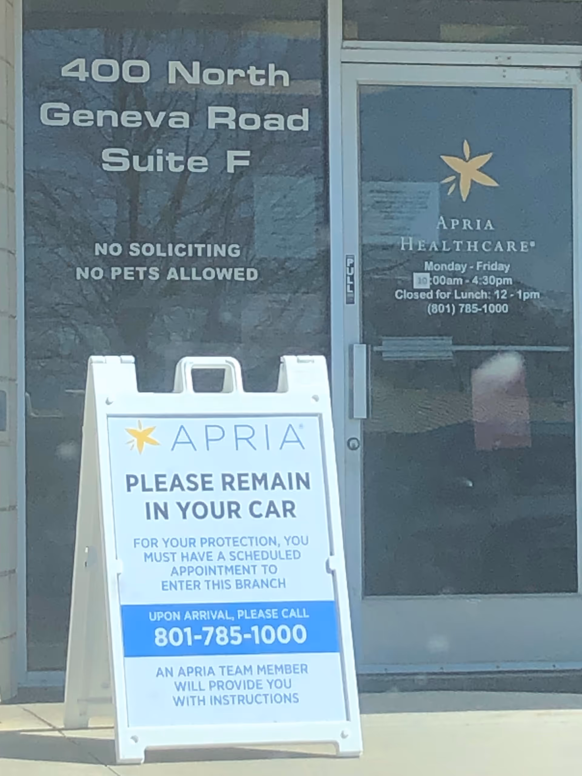 Exterior glass doors display Apria Healthcare signage and a 'Please remain in your car' sign.