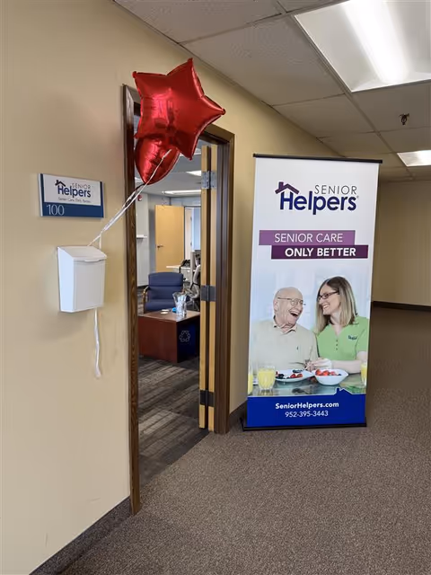 Interior hallway of a Senior Helpers facility with doorway, banner, and red star balloon.