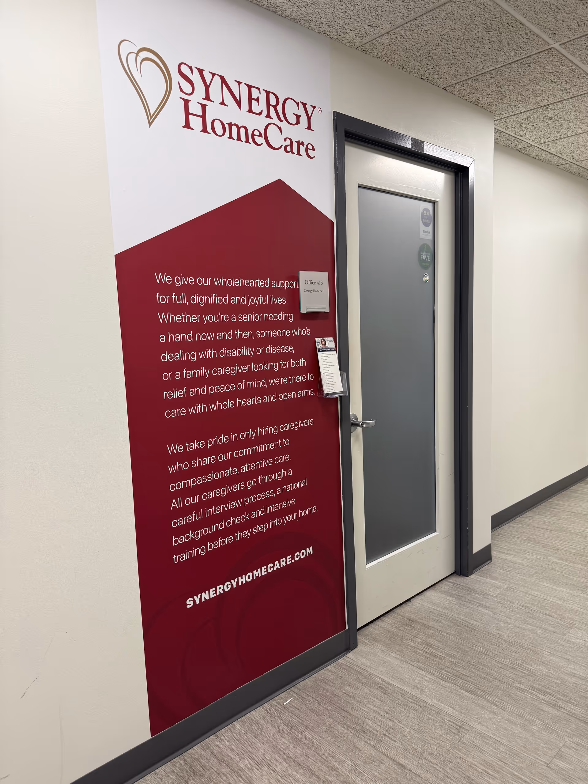 Interior hallway featuring a large SYNERGY HomeCare sign beside a door.
