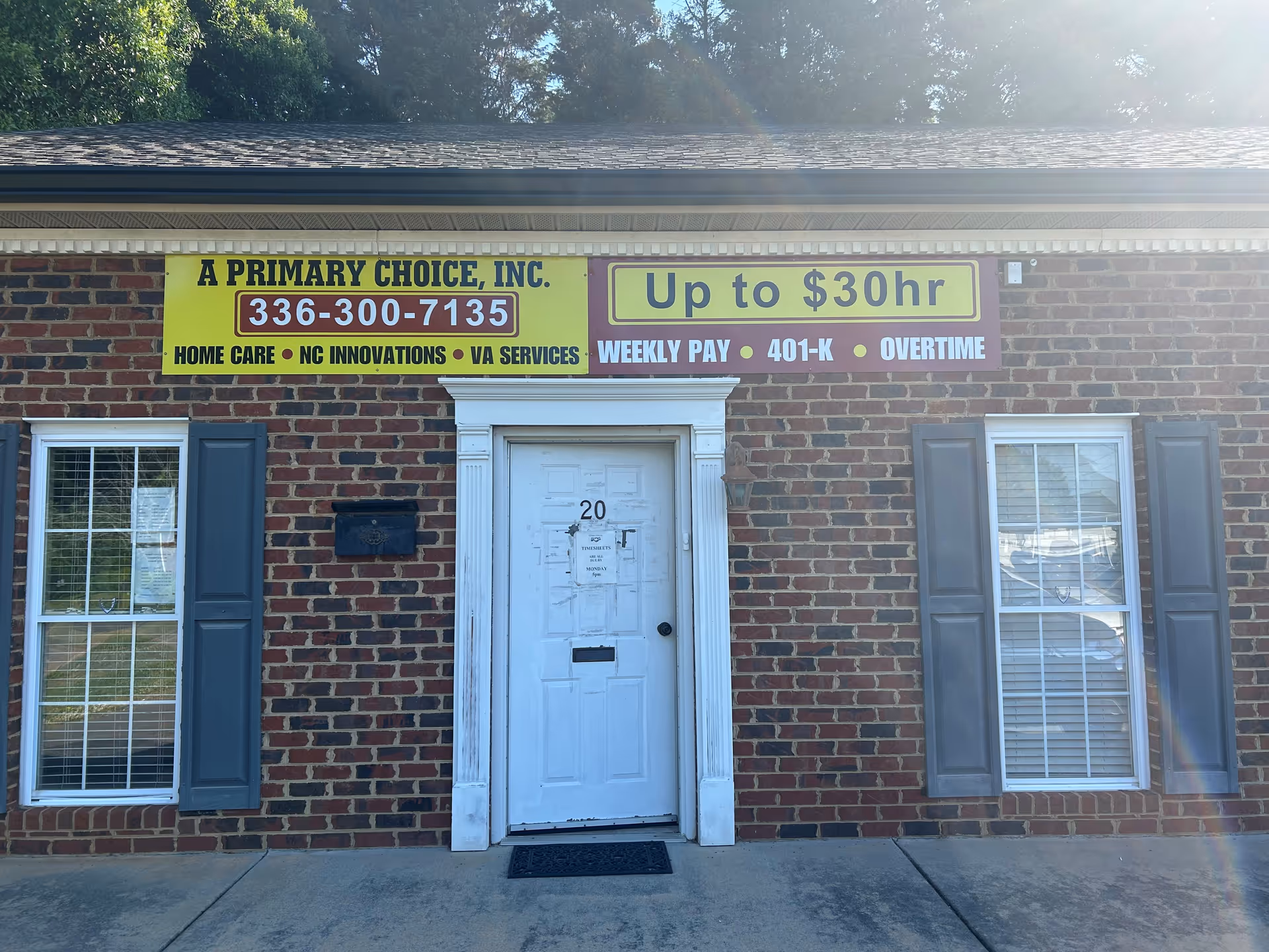 Brick storefront with two windows, a white door, and yellow signage advertising home care.