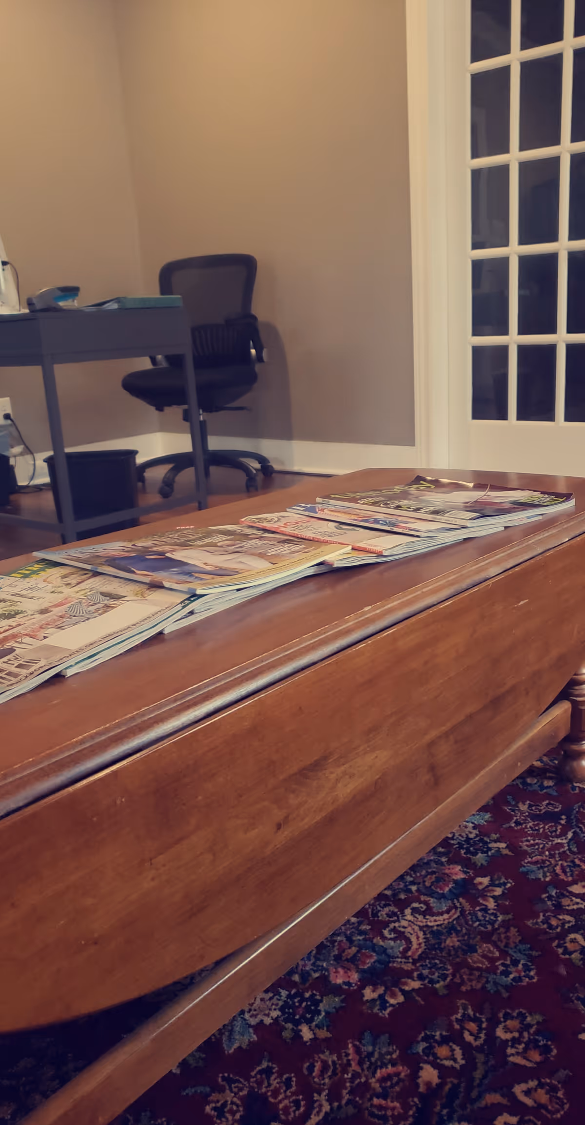 Interior lounge with a desk, chair, glass door, and magazines on a coffee table.