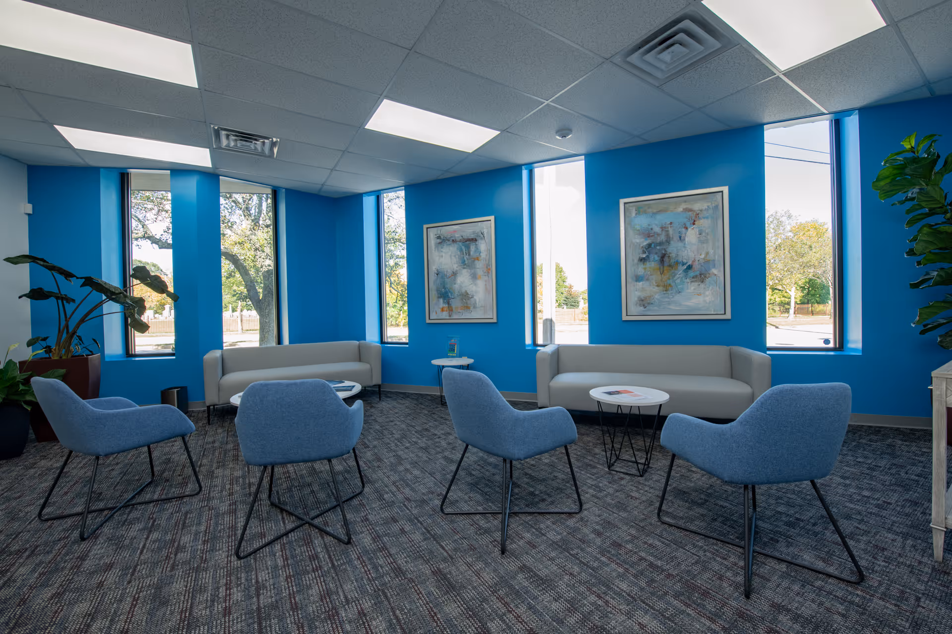 Bright blue lounge with modern chairs and sofas in a calm senior living common area.