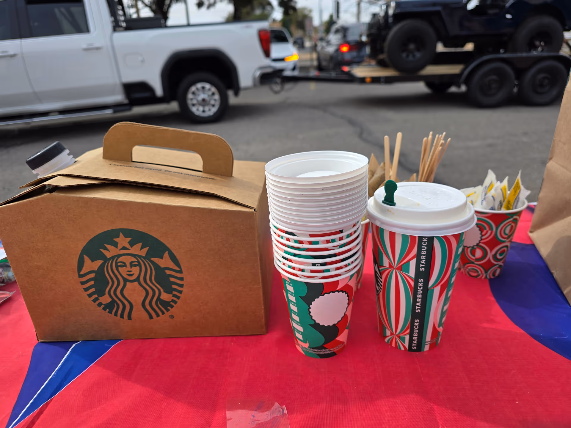 Starbucks box and cups on a colorful outdoor table.