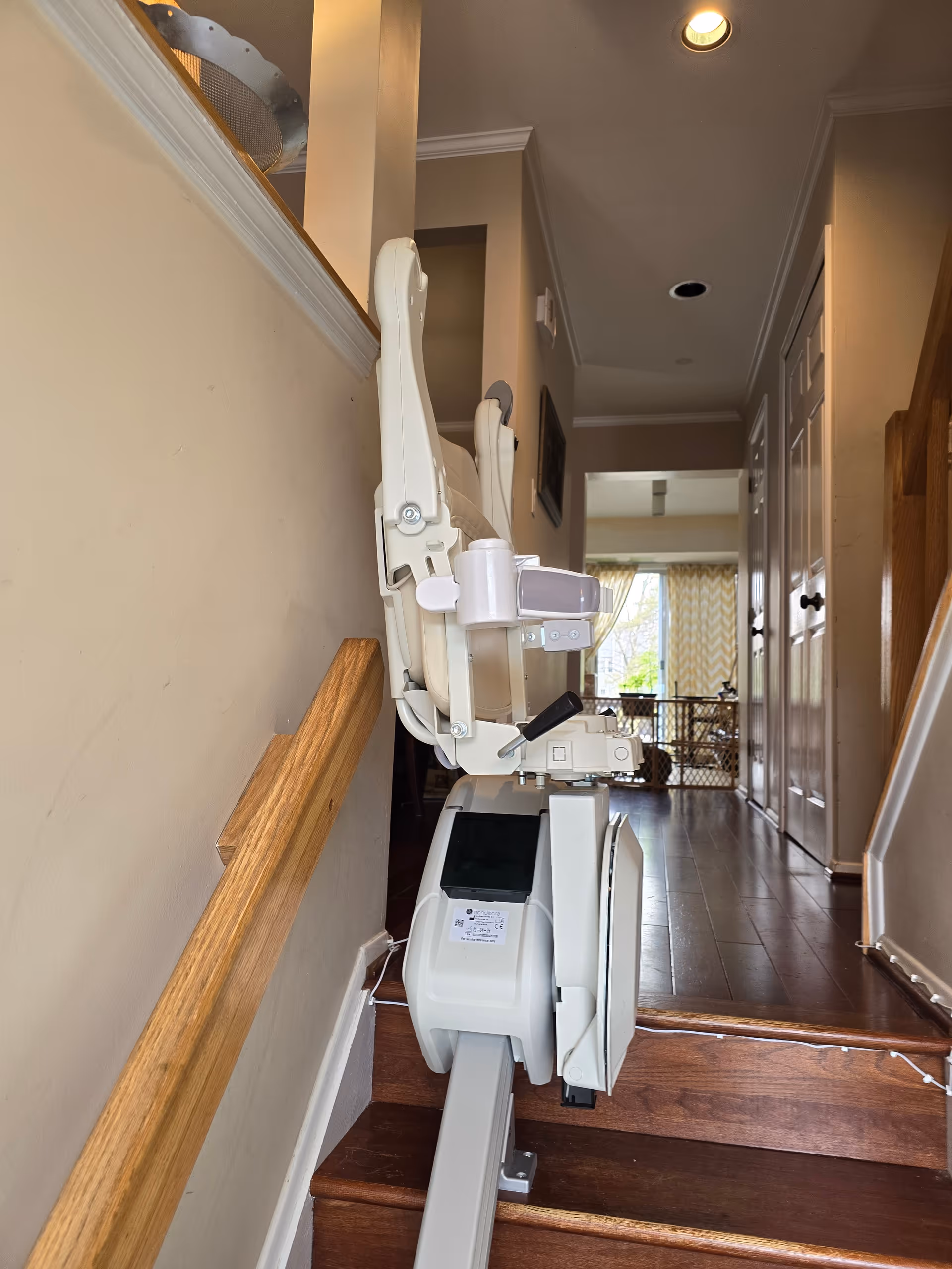 Stair lift chair installed along a hallway staircase in a senior living facility.