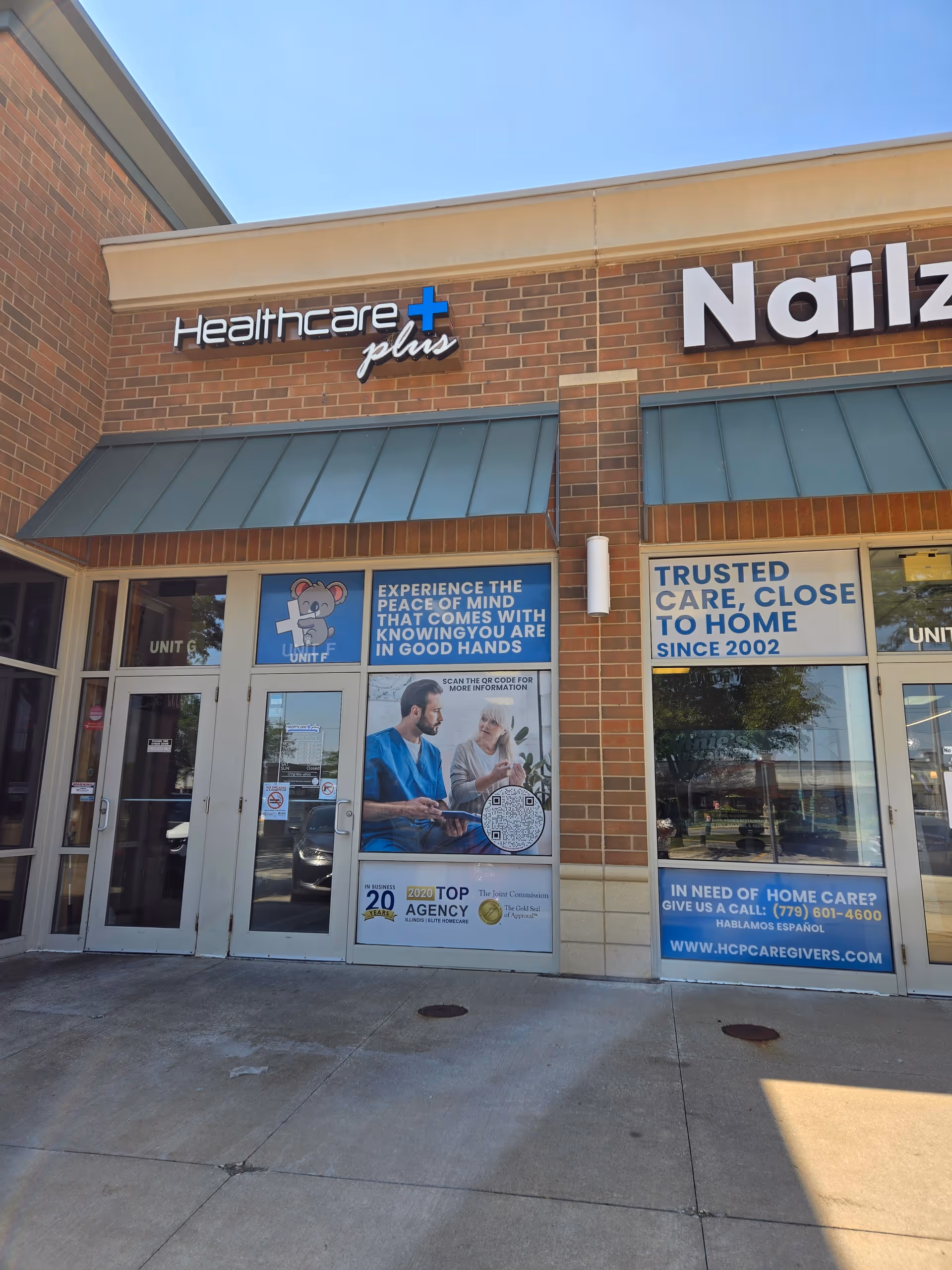 Brick storefront shows Healthcare Plus Caregivers signage and promotional posters on glass windows.