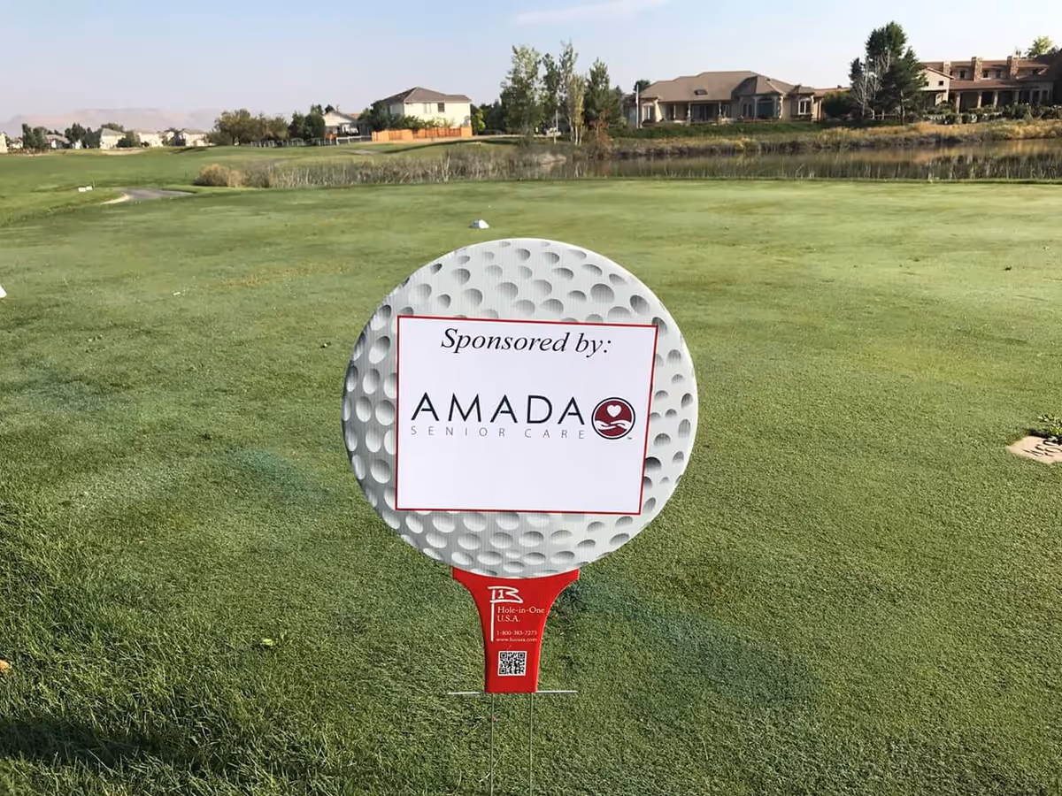 Golf course green with sponsor sign for Amada Senior Care in the foreground.