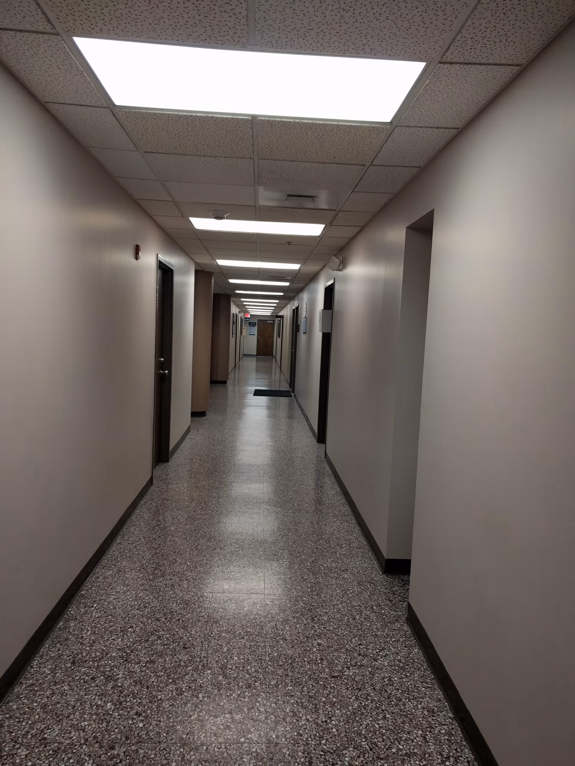 Long sterile hallway in a facility with doors along both walls.