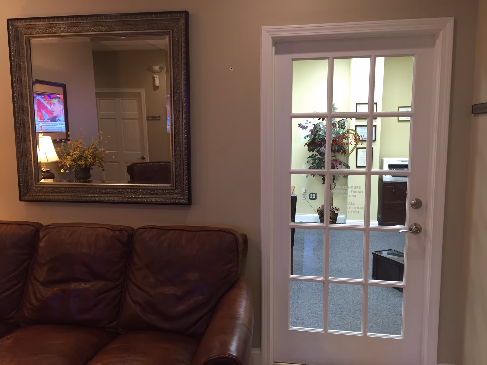 Brown leather sofa in a living area with a framed mirror and glass-paneled door.
