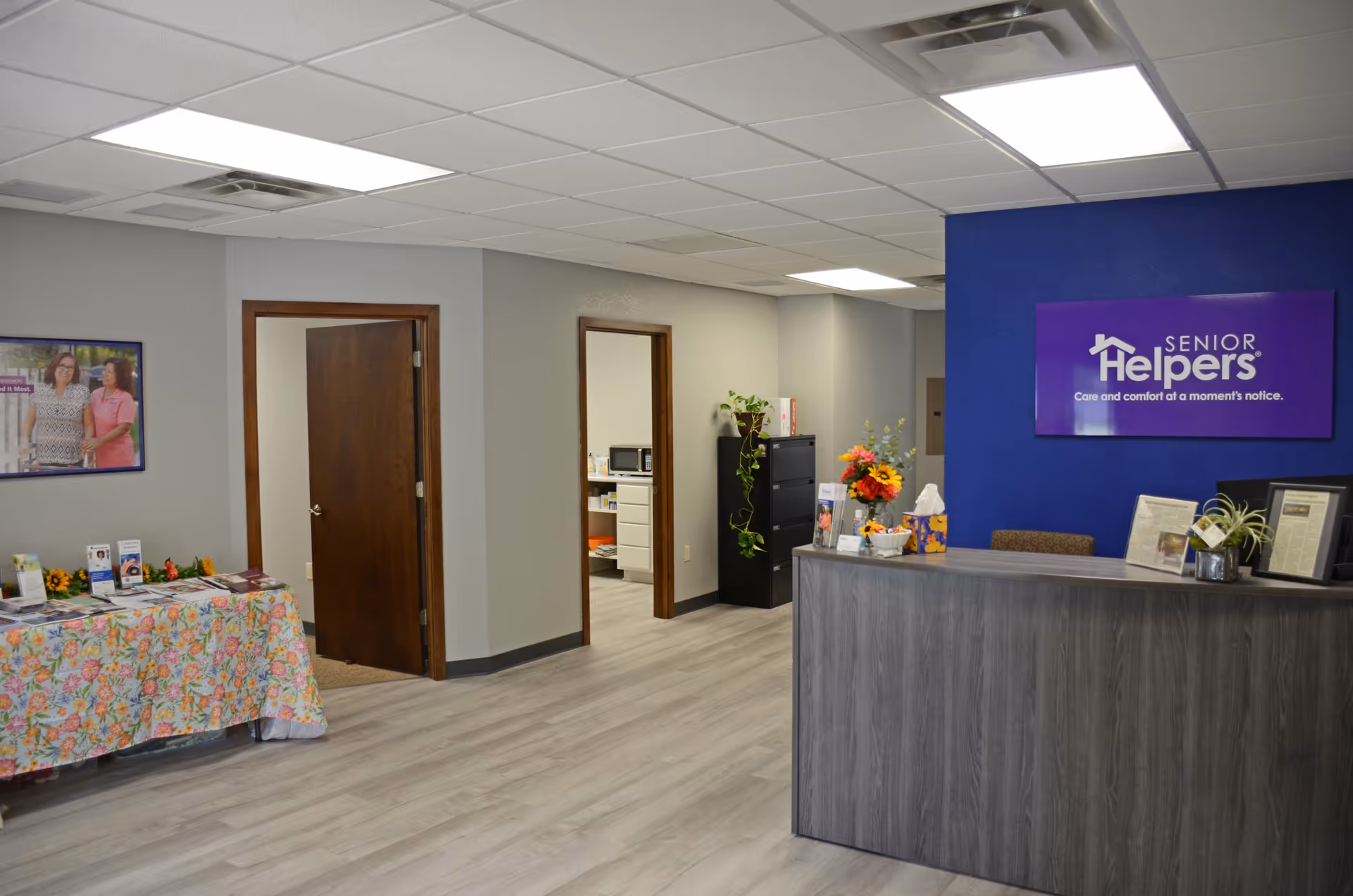 Interior reception area of Senior Helpers with a front desk, blue accent wall, and brochures.