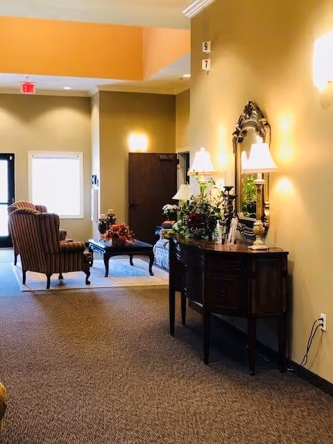 Lobby-style hallway with upholstered chairs, a coffee table, console table, lamps, and a mirror.