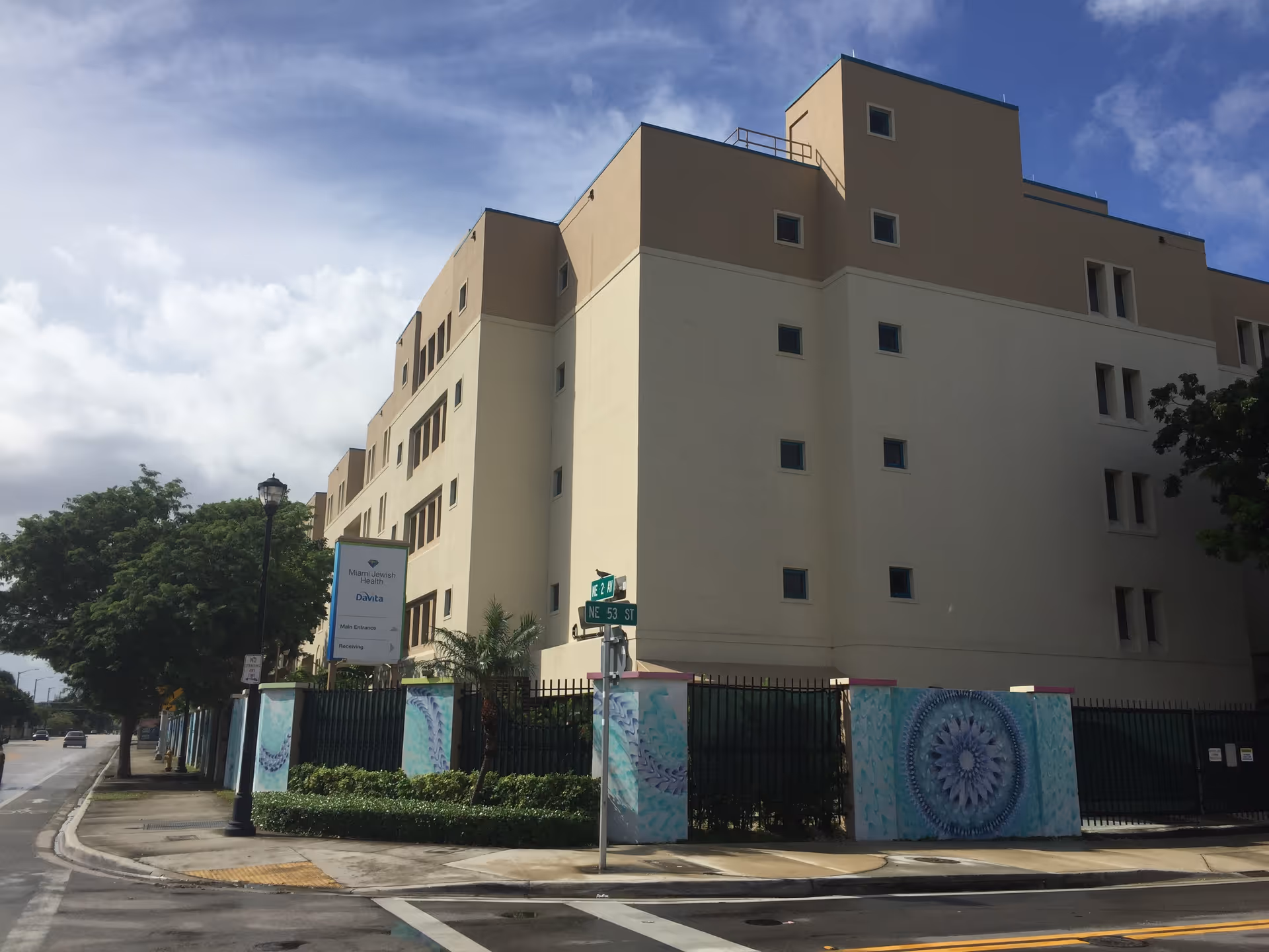 Exterior view of a multi-story beige senior living building surrounded by a fence.