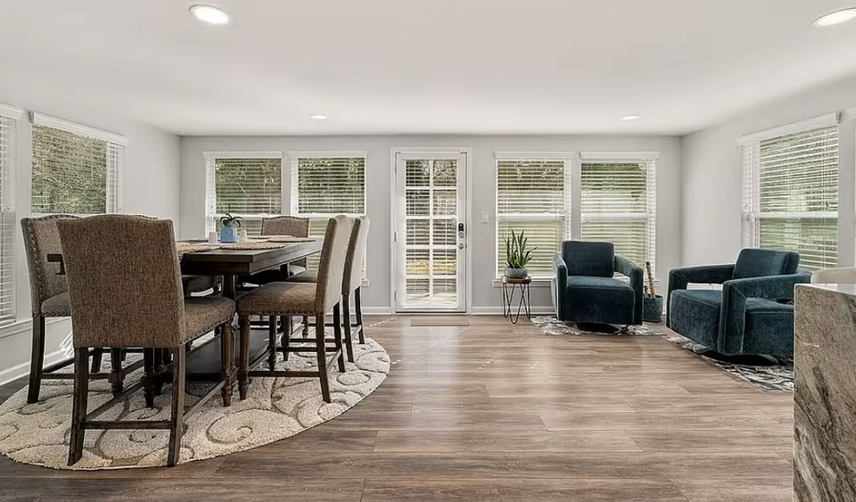 Bright open living area with a dining table, chairs, and glass doors.