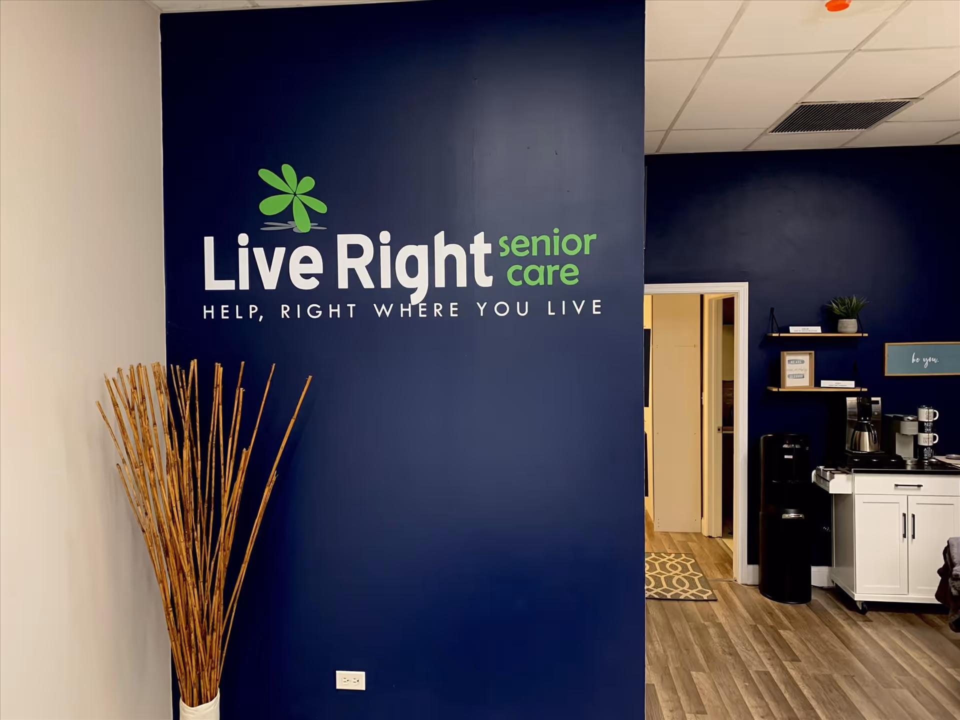 Blue wall with Live Right senior care logo, plant on left, doorway to right.