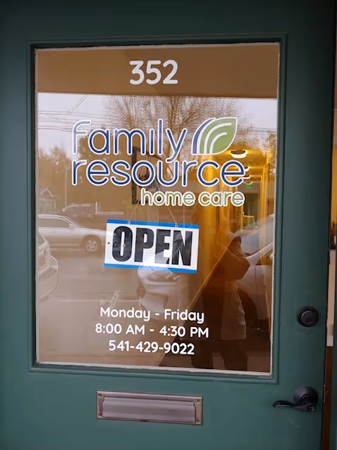 Green door entrance showing Family Resource Home Care sign, OPEN sign, and business hours.
