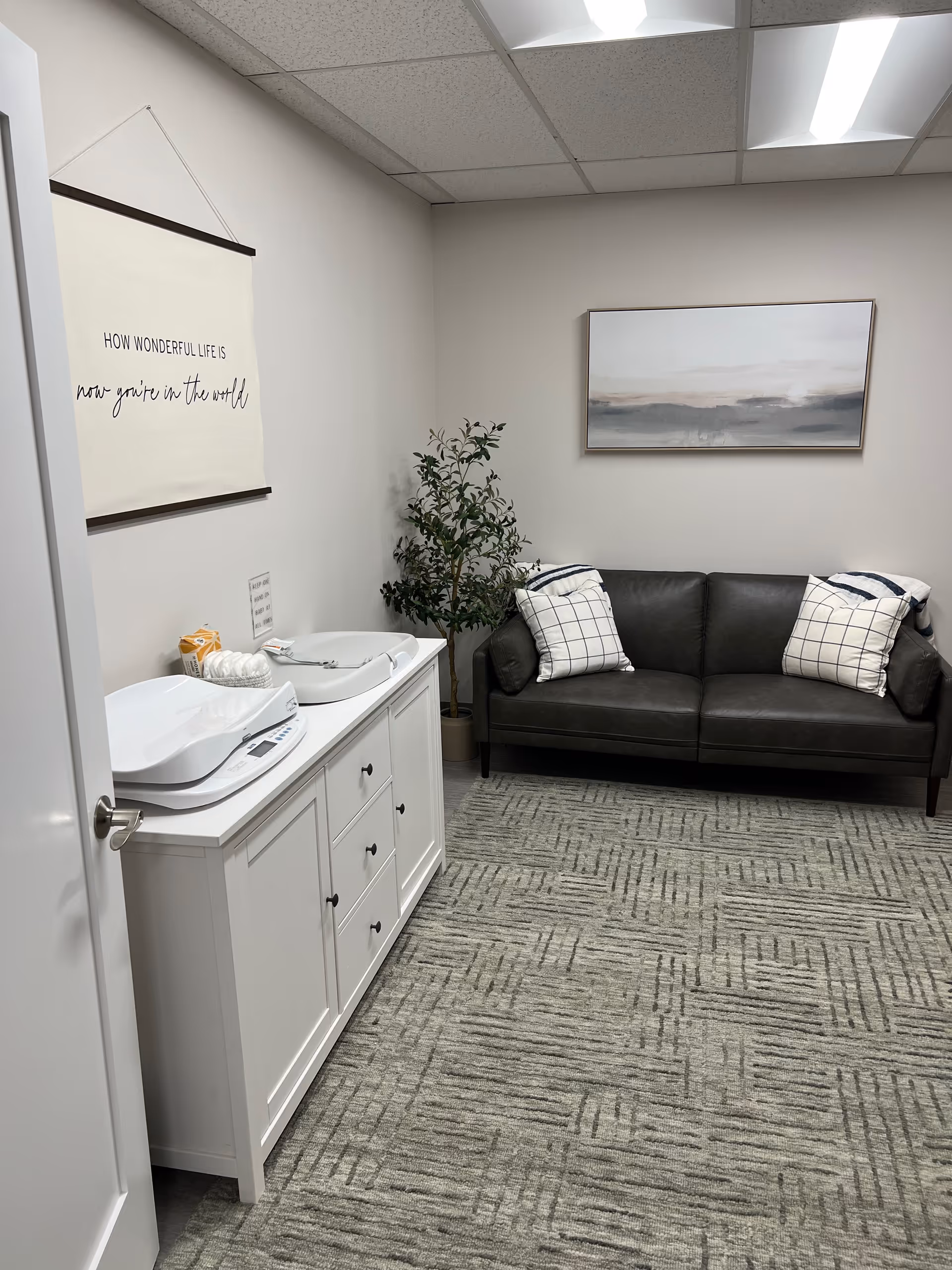 A small interior lounge with a white cabinet and breast pump devices beside a couch.
