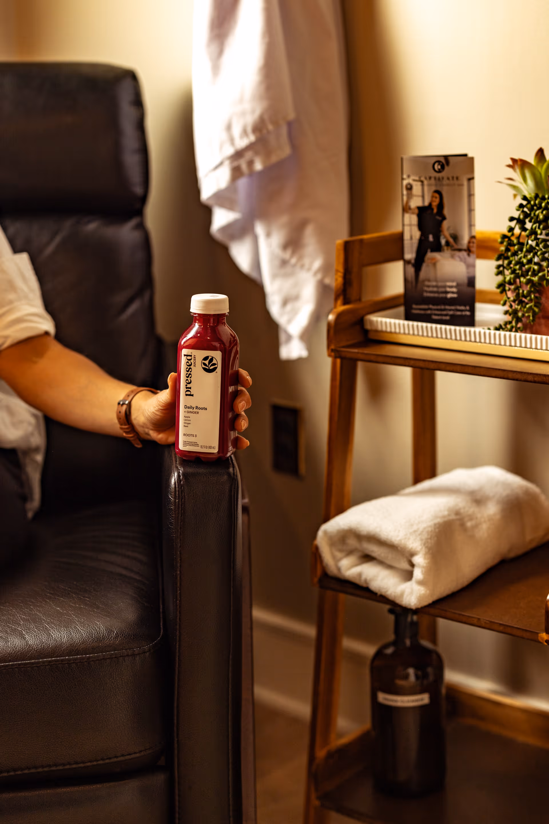 Person seated in a chair near a beauty bar holds a red beverage bottle.