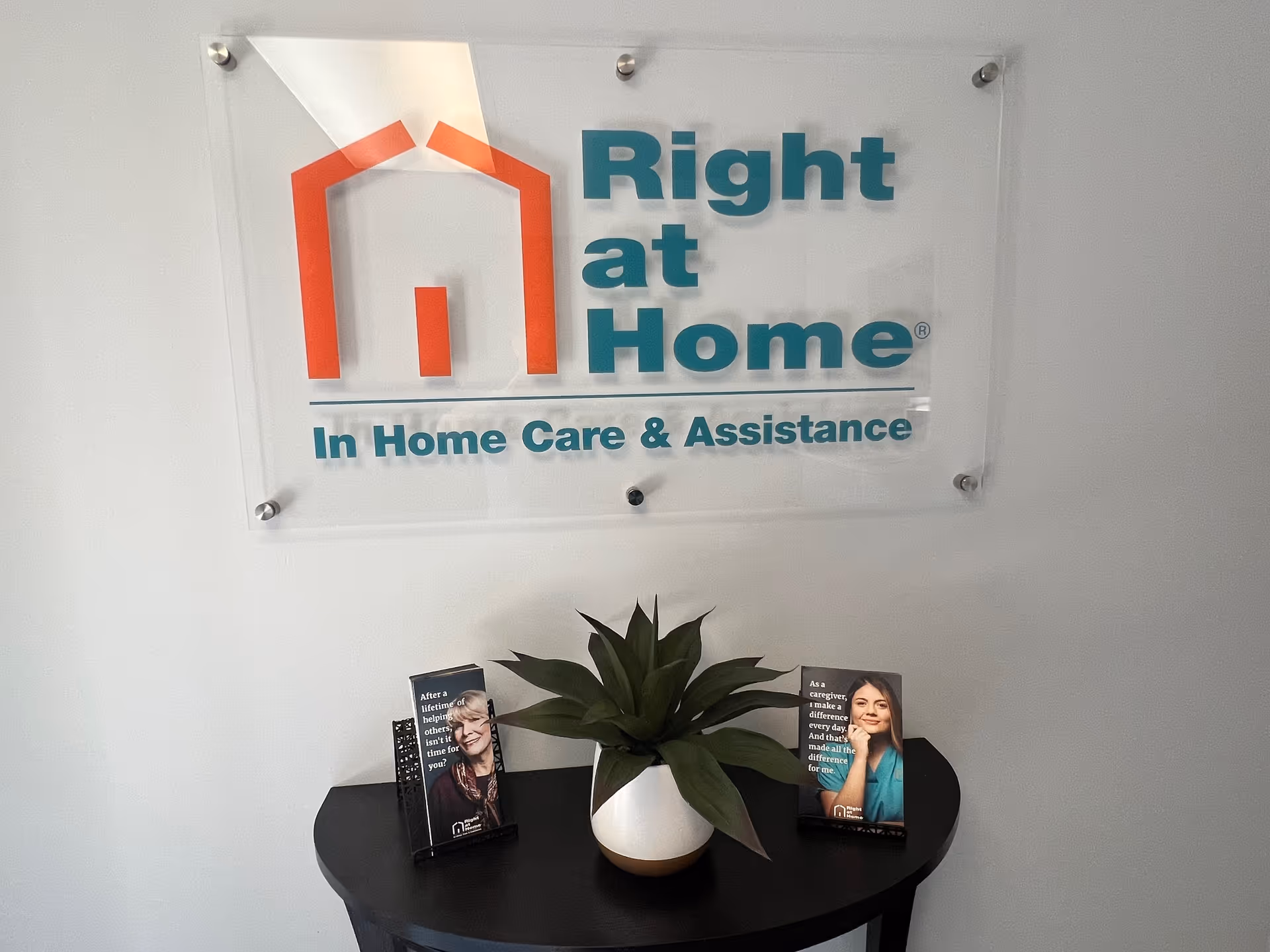Interior wall with Right at Home sign, small table, plant, and brochures