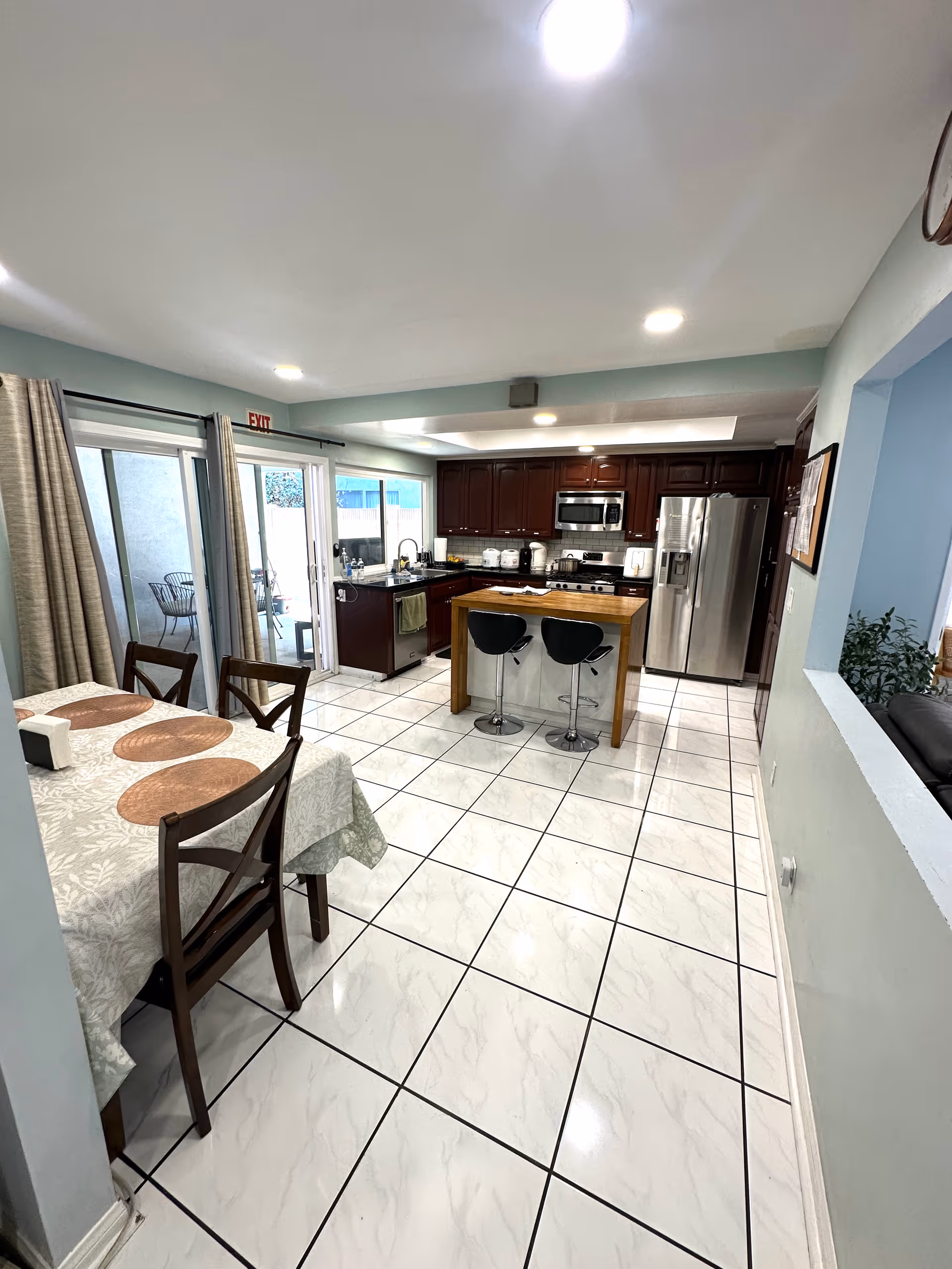 Bright open kitchen with dark wood cabinets, stainless appliances, island, and adjacent dining table.
