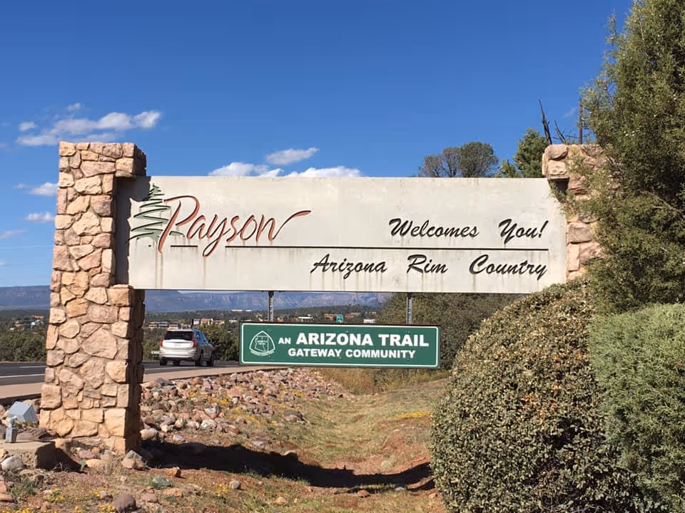 Exterior roadside sign reading Payson Welcomes You and Arizona Rim Country beneath blue sky