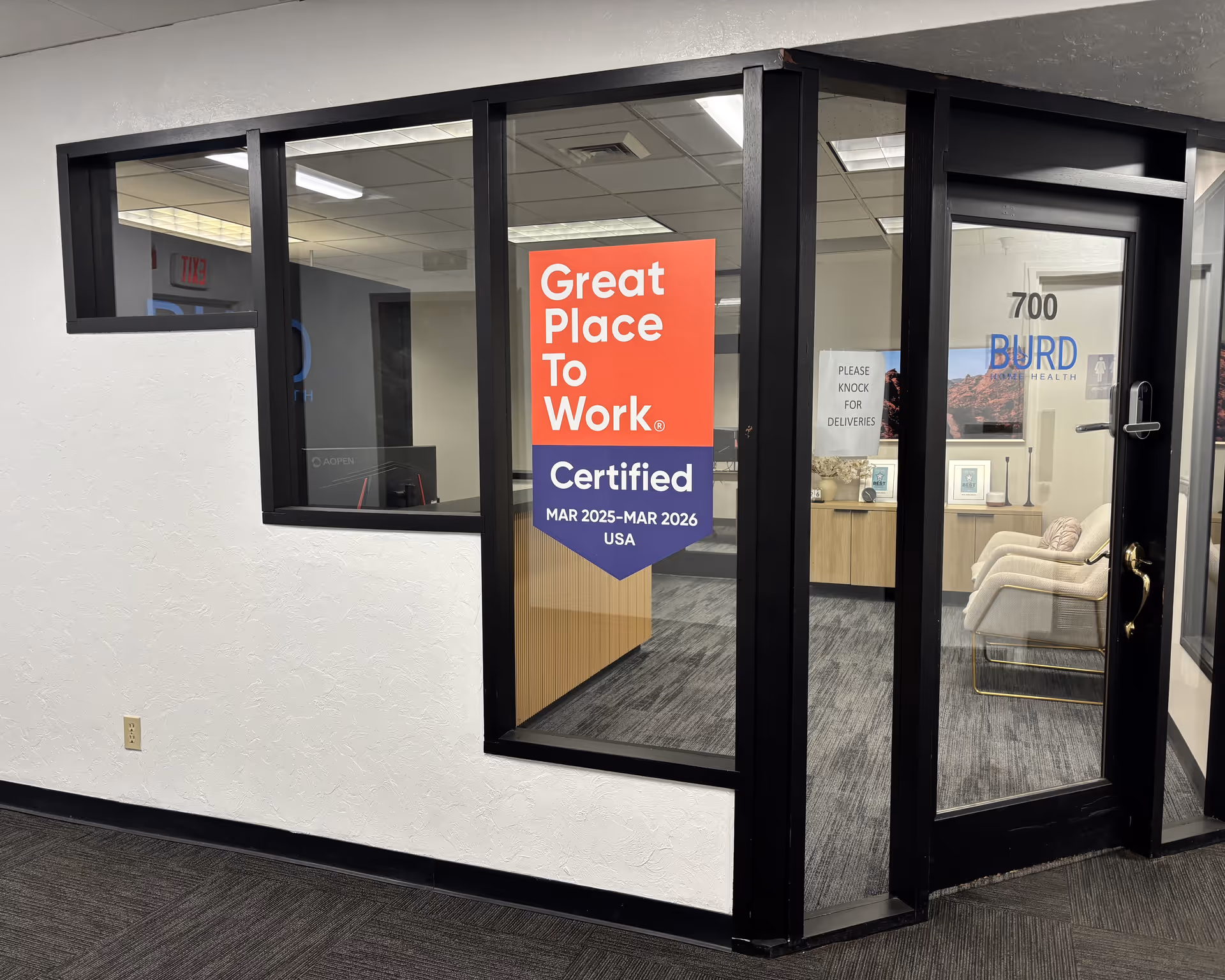 Indoor lobby with glass doors and a 'Great Place To Work' banner.