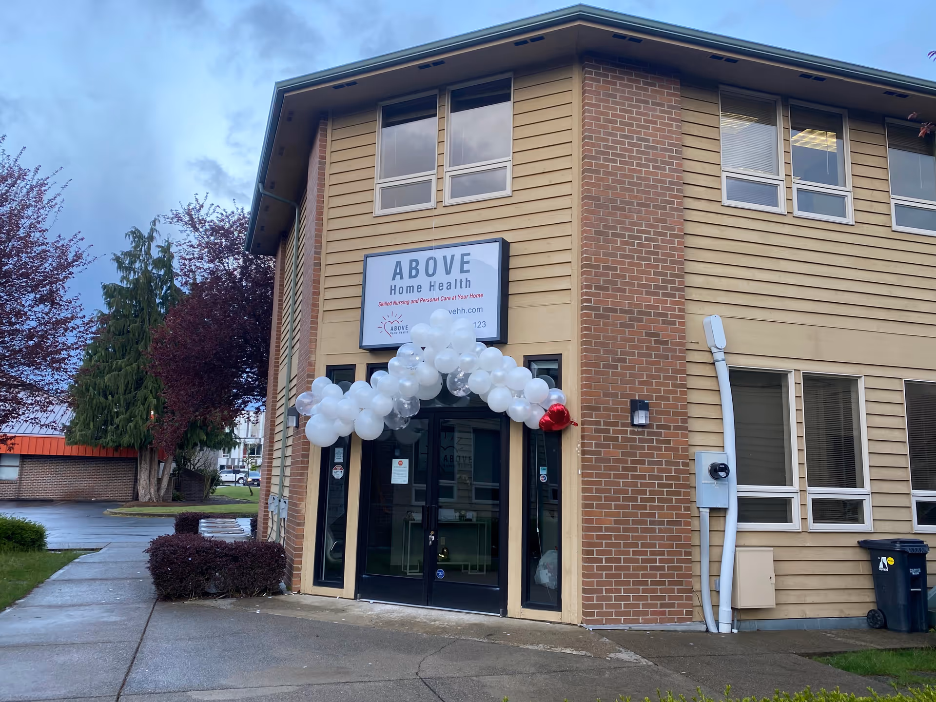 Exterior view of ABOVE Home Health facility with a balloon arch at the entrance