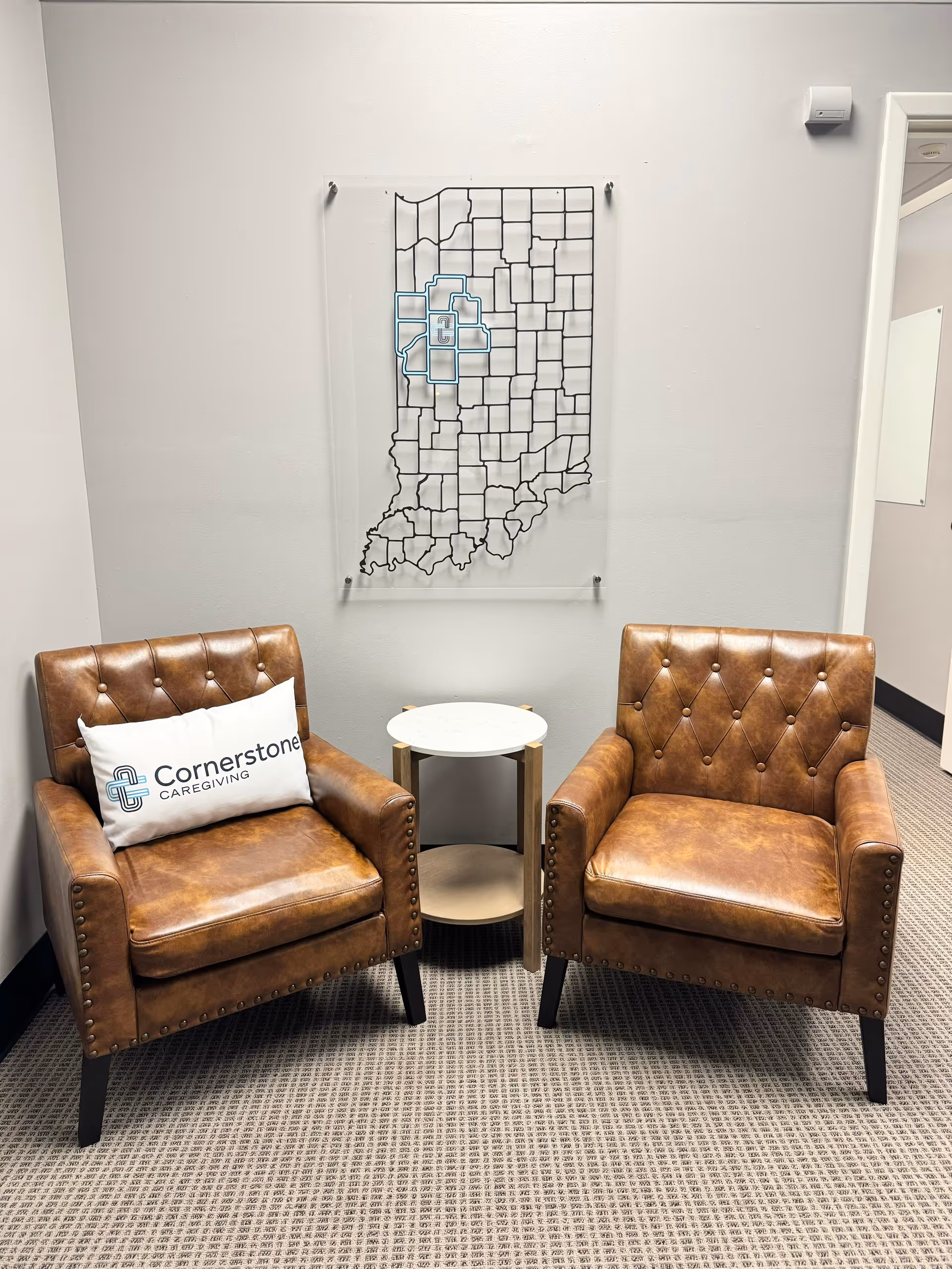 Two brown leather armchairs with a white round table before a wall map.