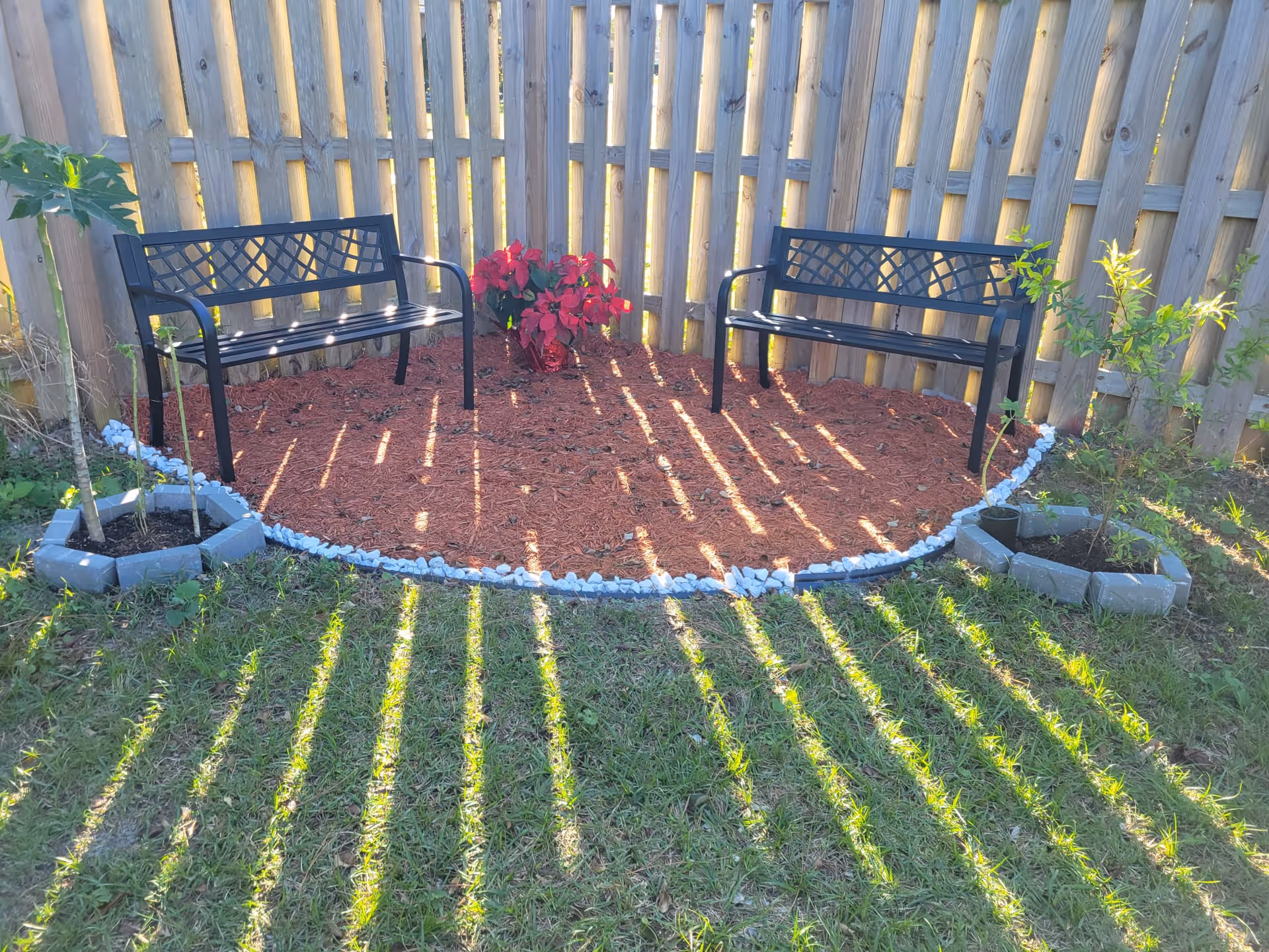 Two black metal benches face each other in a circular outdoor seating area.