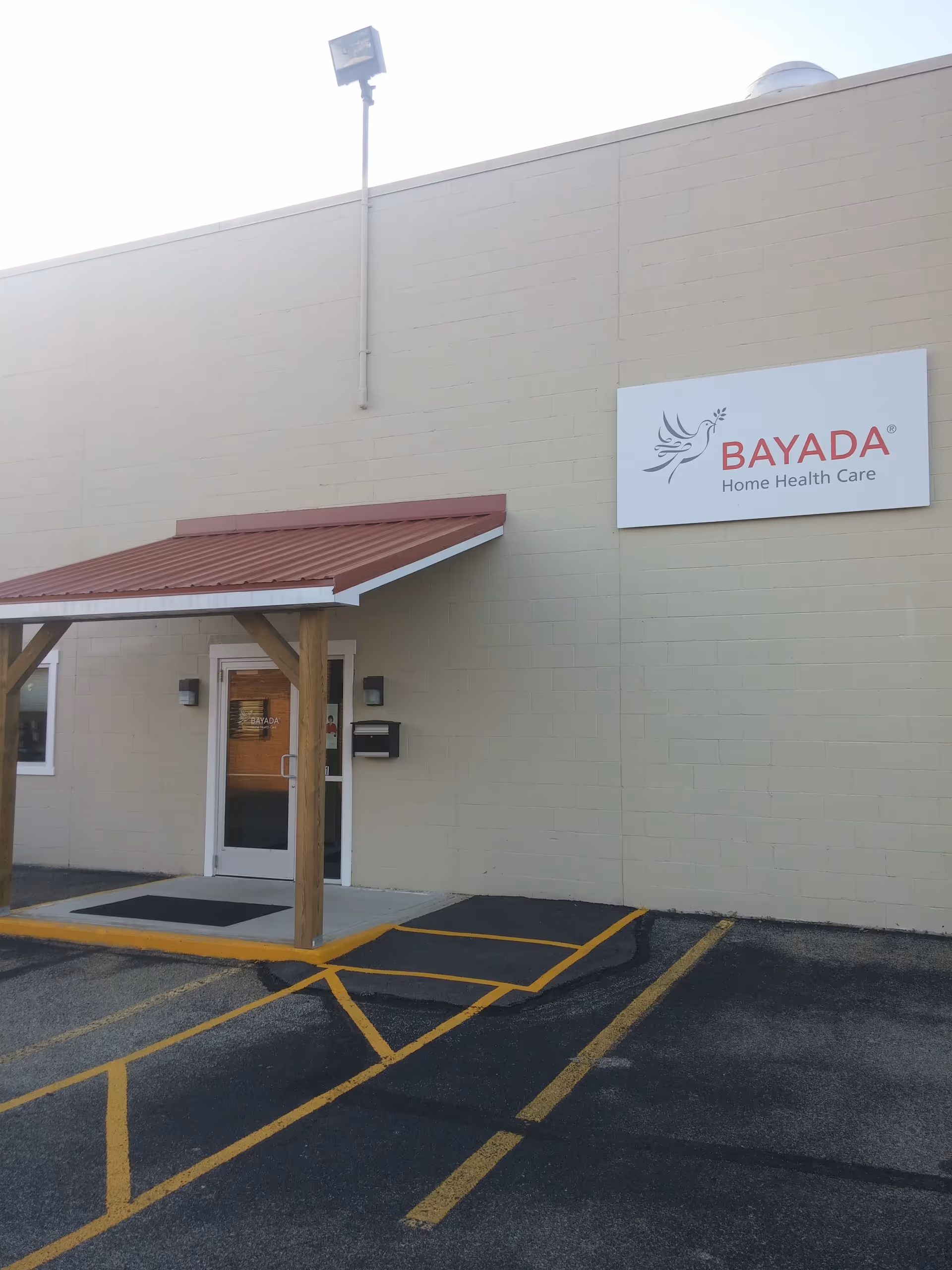 Exterior view of a BAYADA building with a sign, entrance, and red awning.