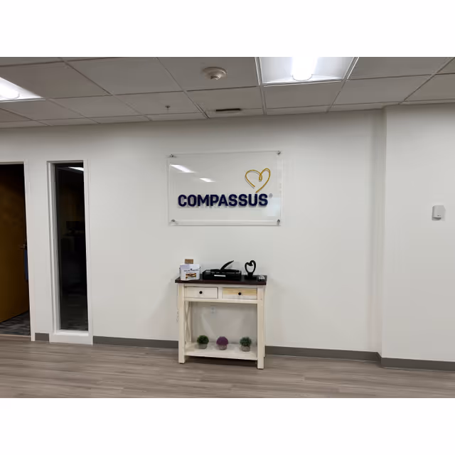 Interior lobby featuring a Compassus sign and a small console table.