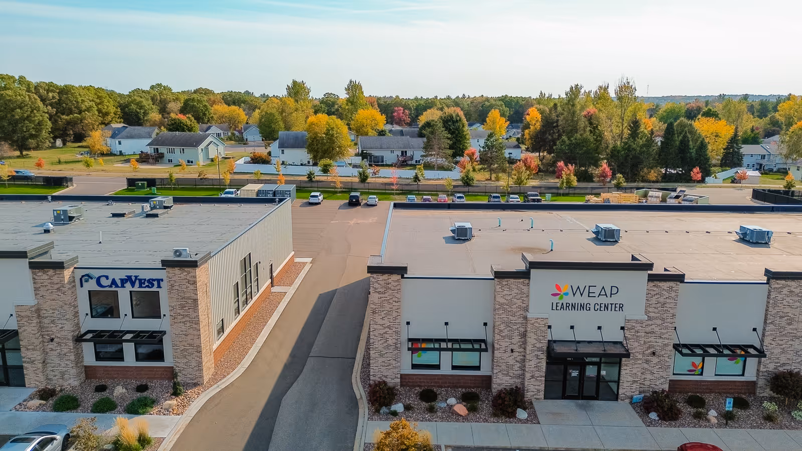 Front view of WEAP Learning Center building with autumn trees and parked cars nearby.
