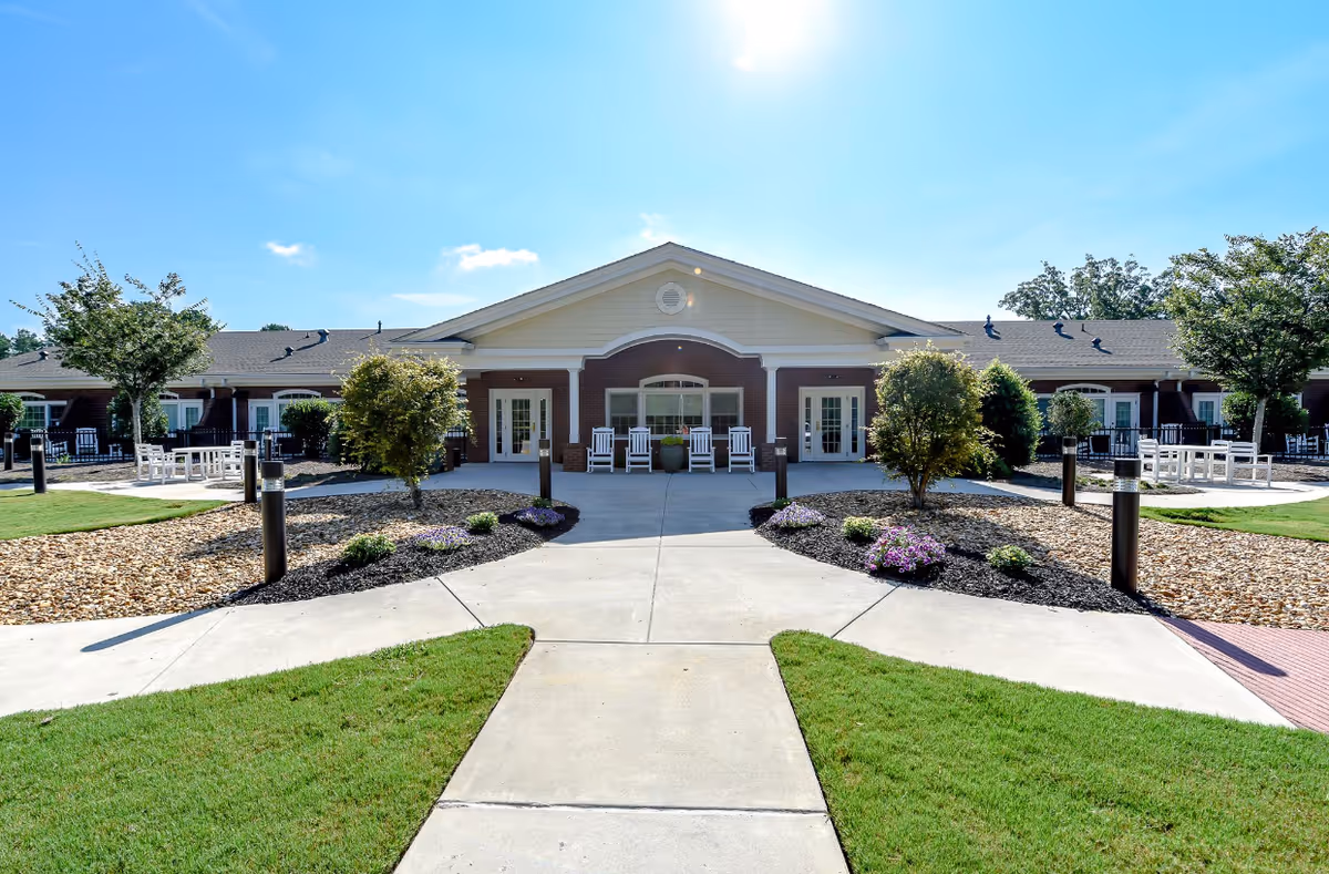 Sunny exterior view of Brightmoor Hospice building with pathways, landscaping, and outdoor seating.
