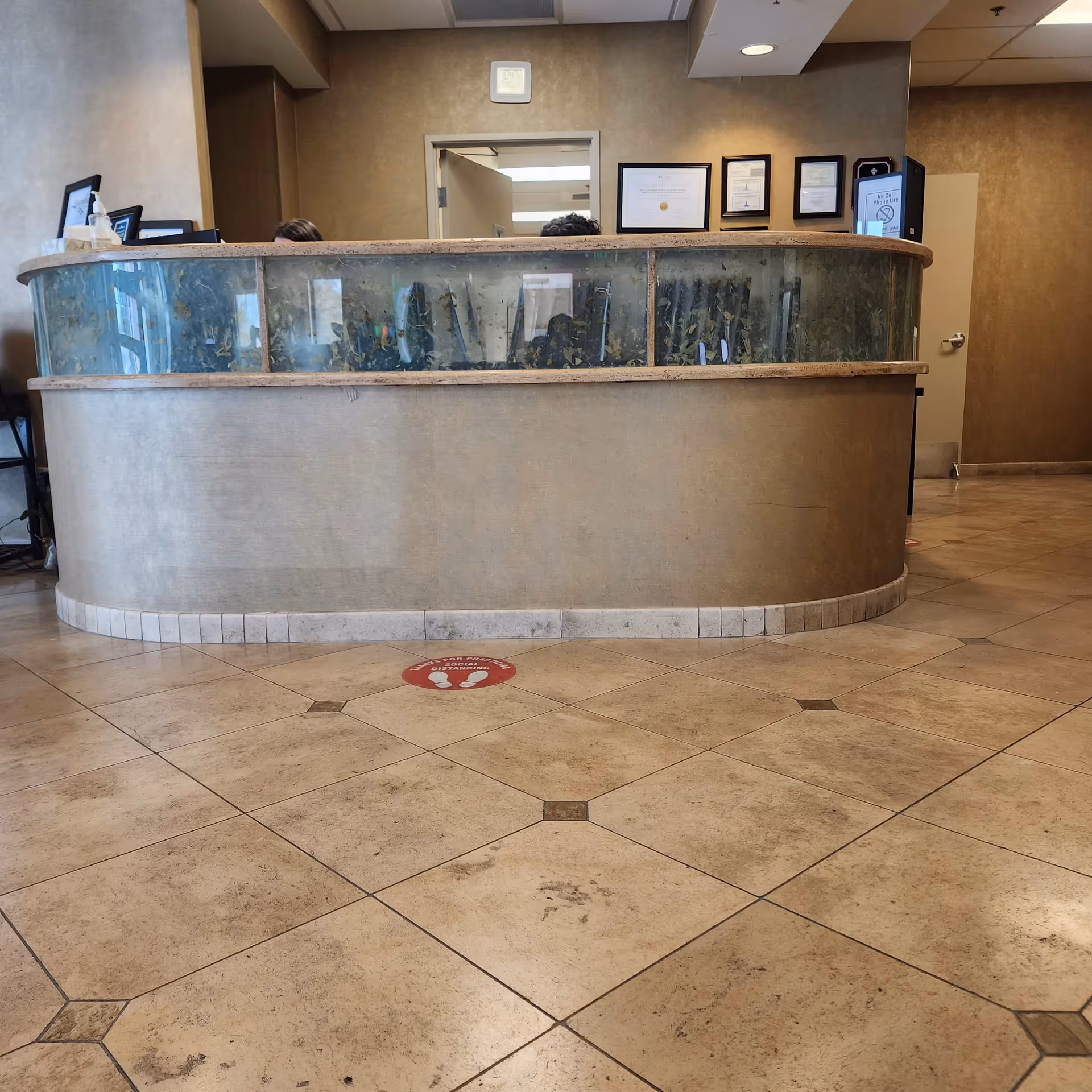 Curved reception desk with glass panels in a beige-tiled interior lobby.
