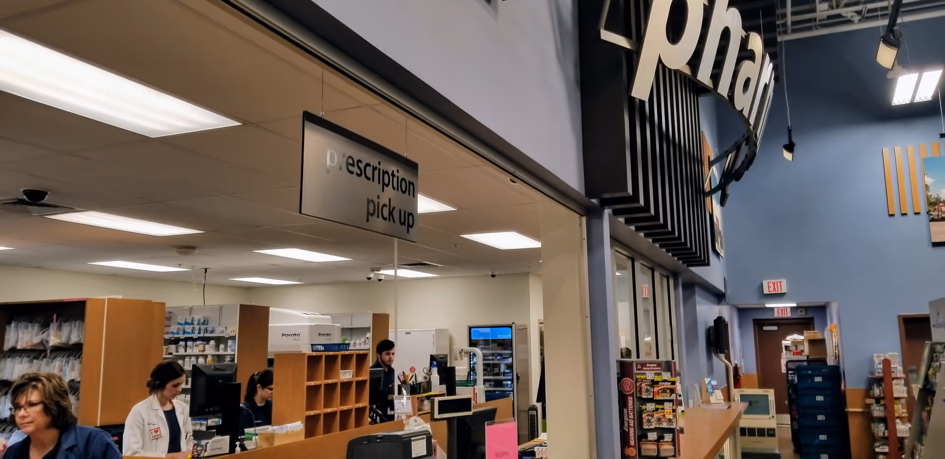 Pharmacy counter inside Kroger with staff assisting customers at prescription pickup.