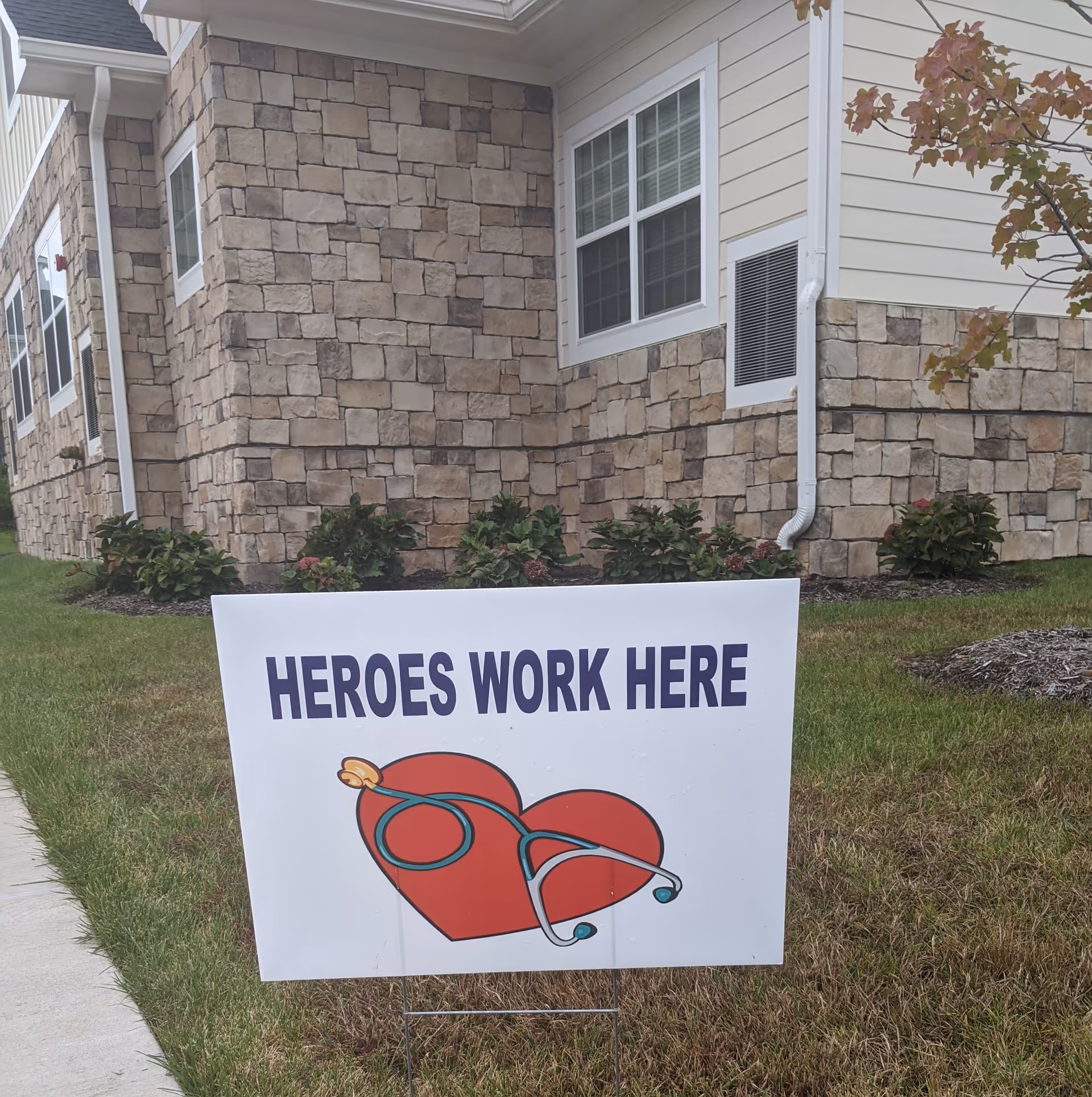 Exterior view of a stone-clad building with a lawn sign reading Heroes Work Here.