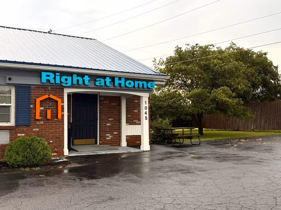 Exterior view of a Right at Home facility with a brick facade, sign, and picnic table.