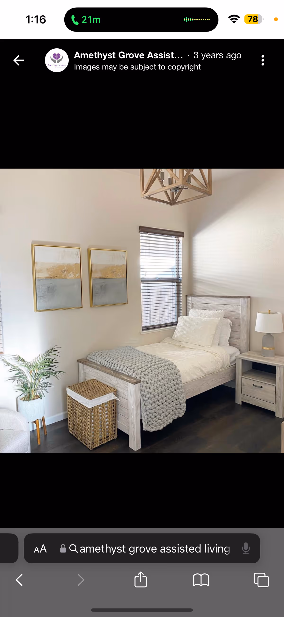 A cozy, furnished bedroom with a single bed, nightstand, window, plant, and wall art.