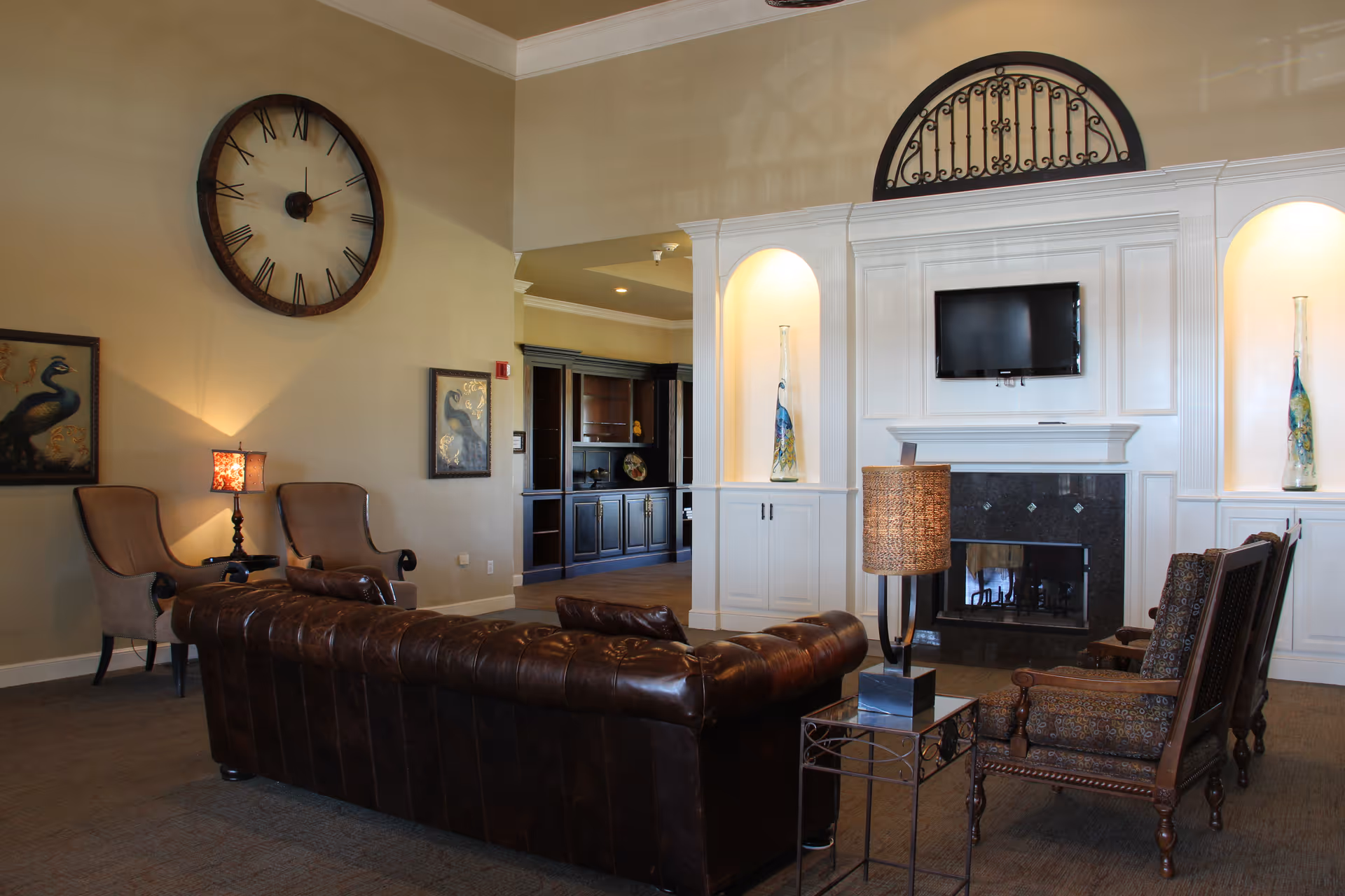 Elegant senior living facility lounge with leather sofa, chairs, fireplace, and mounted TV.