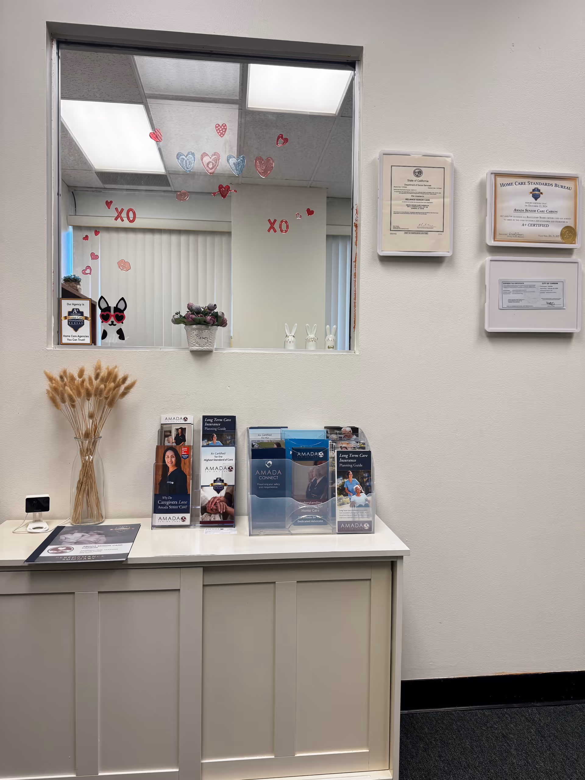 Reception desk with brochures, certificates, window view with heart decals and dried wheat