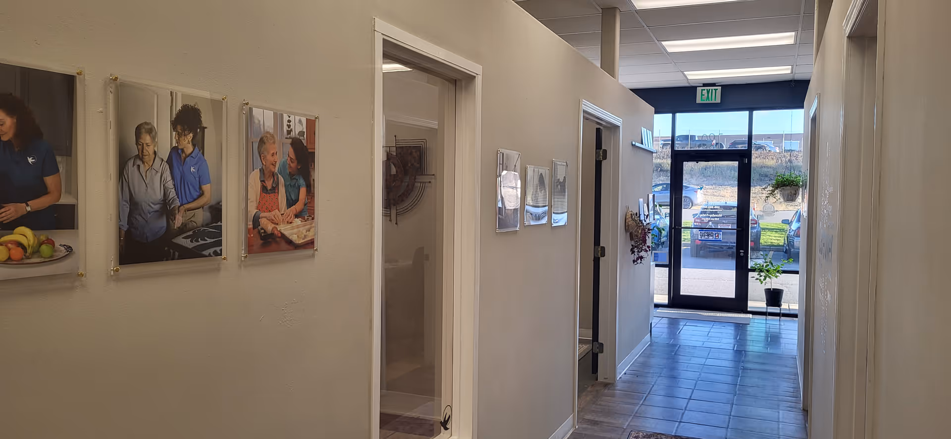 Interior hallway with framed photos on the left and glass doors at the far end