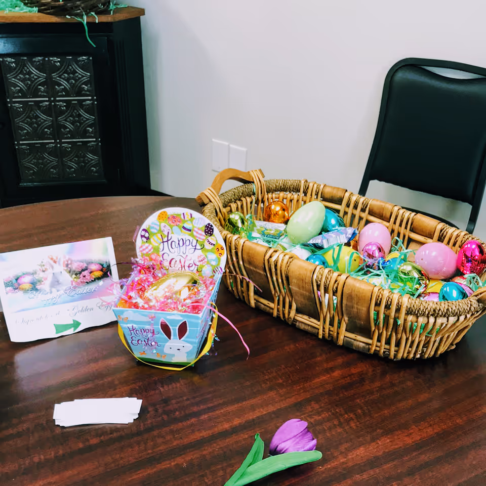 Wooden table holds Easter baskets with colorful eggs and decorative cards in a room
