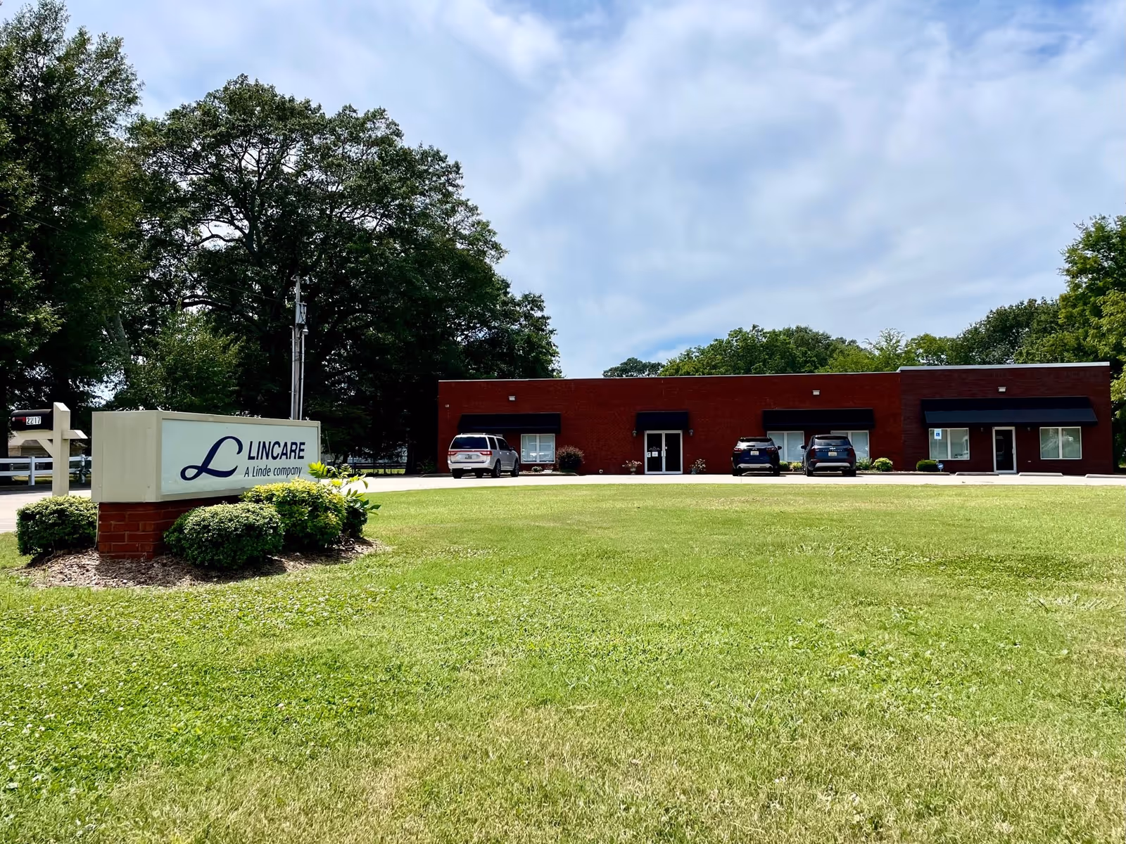 Exterior of LINCARE facility with brick front, sign, and parked cars.