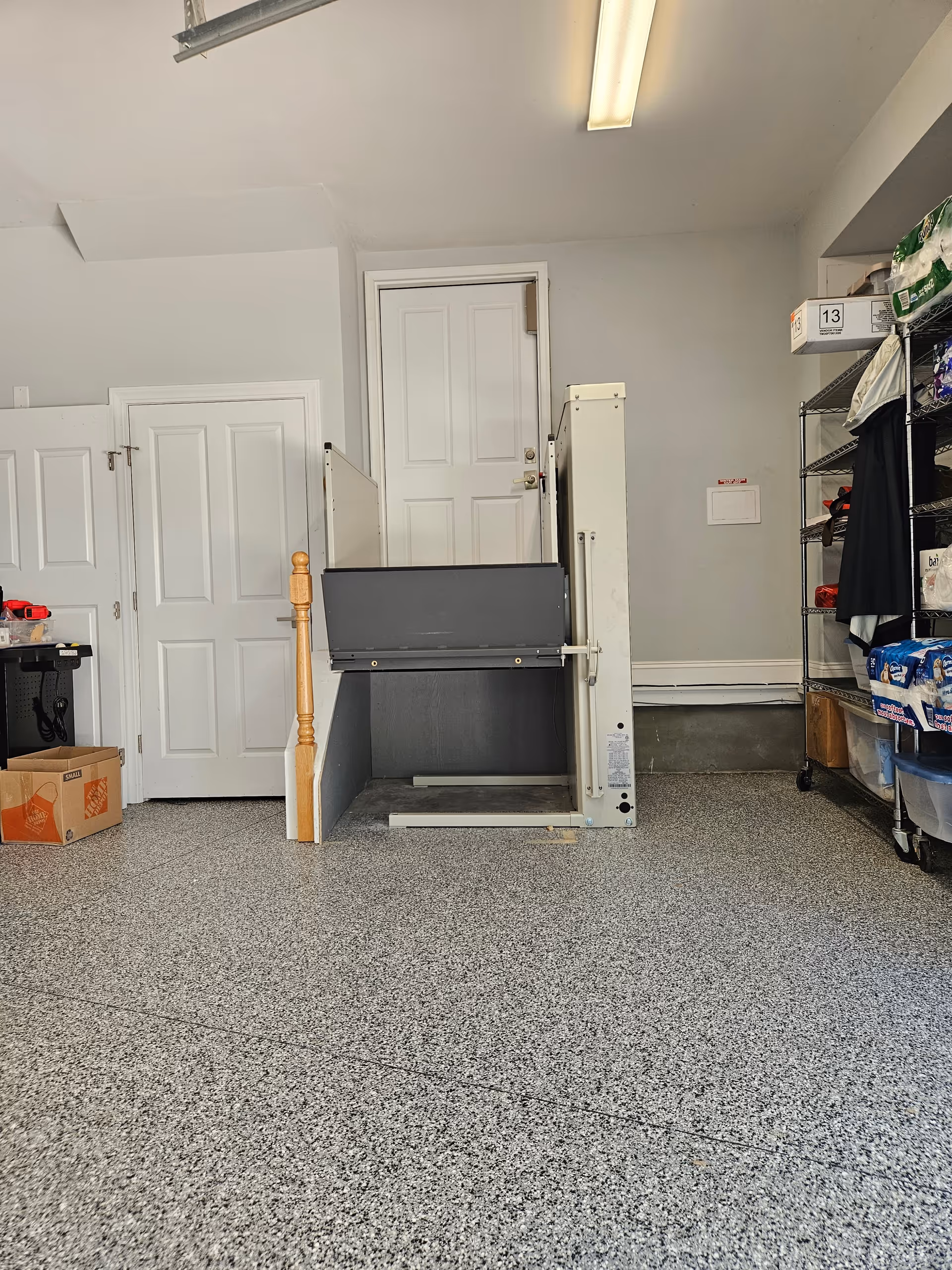 Interior storage area with a stair lift and shelving, doors, and a gray terrazzo floor.