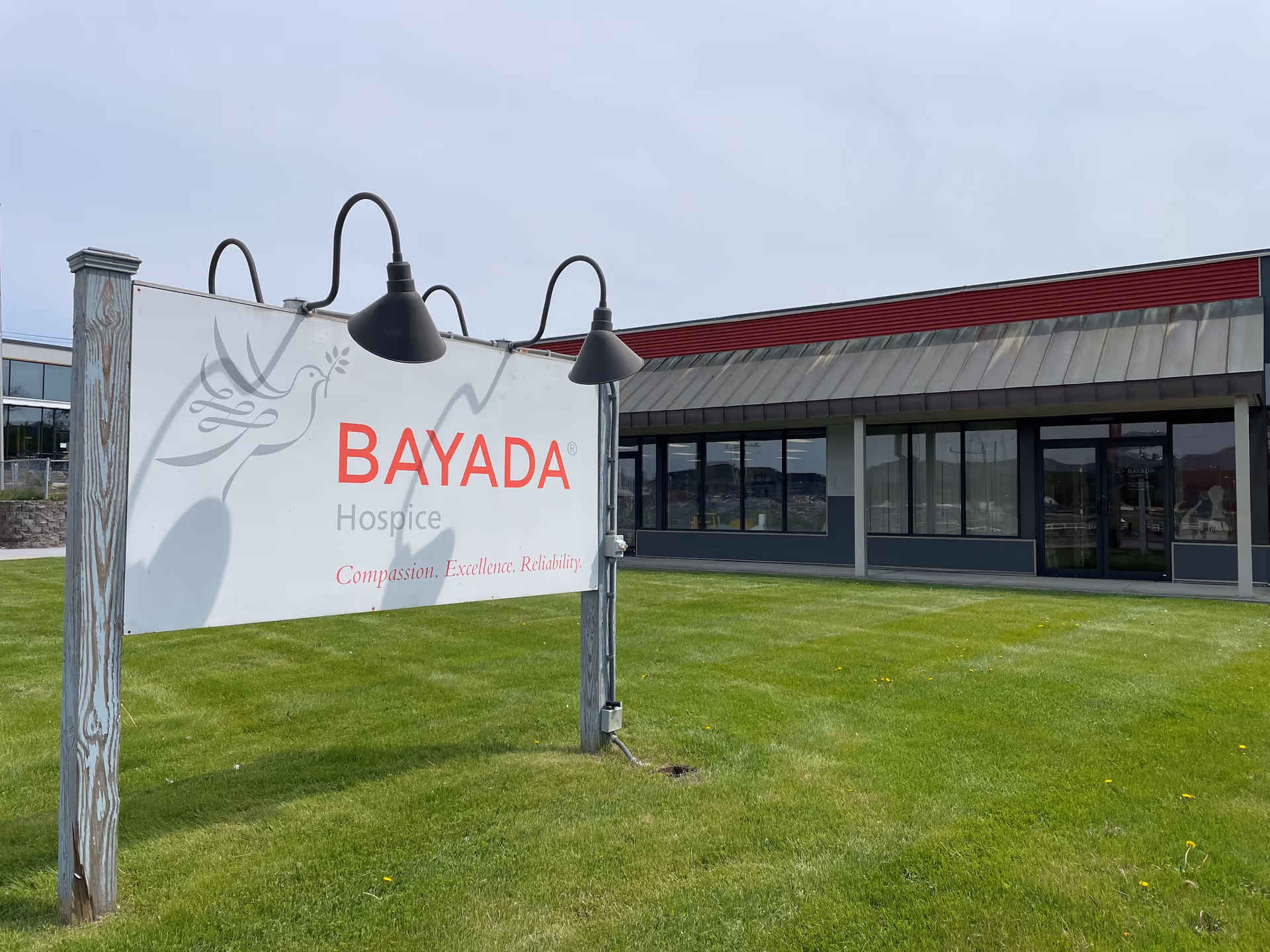 Bayada Hospice sign on a grassy lawn in front of a single-story building.