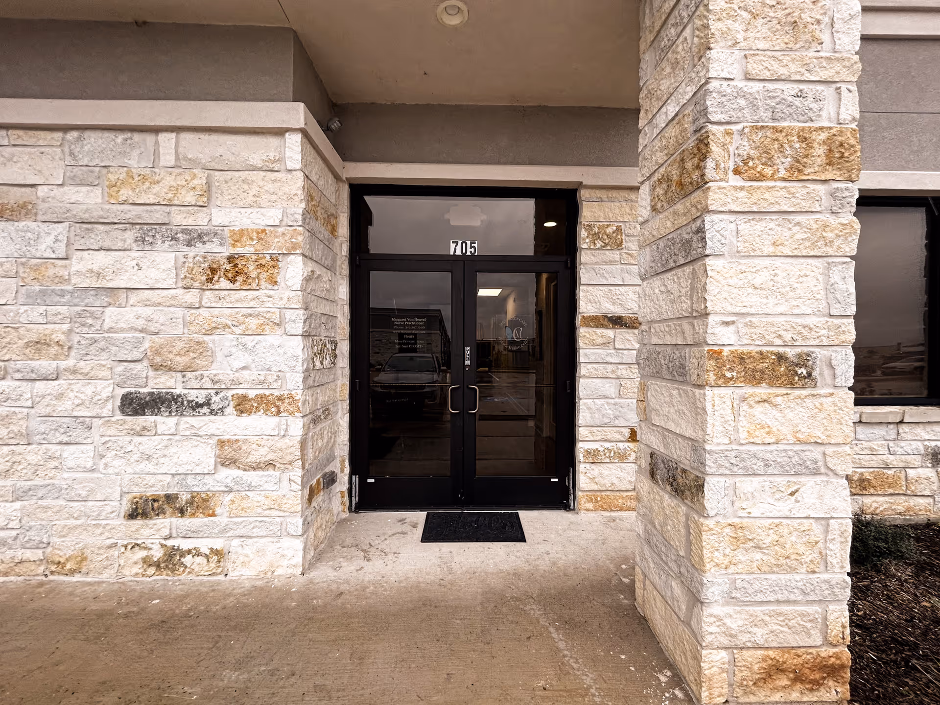 Stone facade with double glass doors and 705, the building entrance to a senior facility.